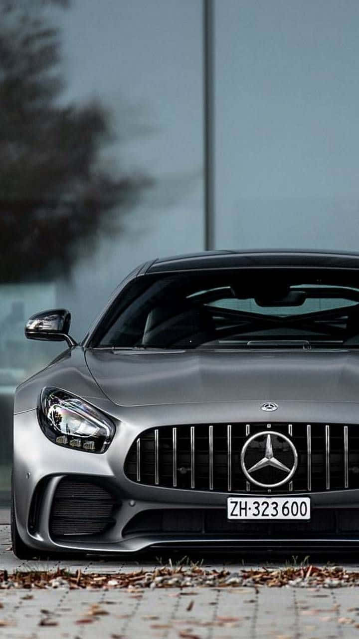 銀色 Mercedes-AMG GT 跑車停泊在行人路上，伴有秋天落葉。