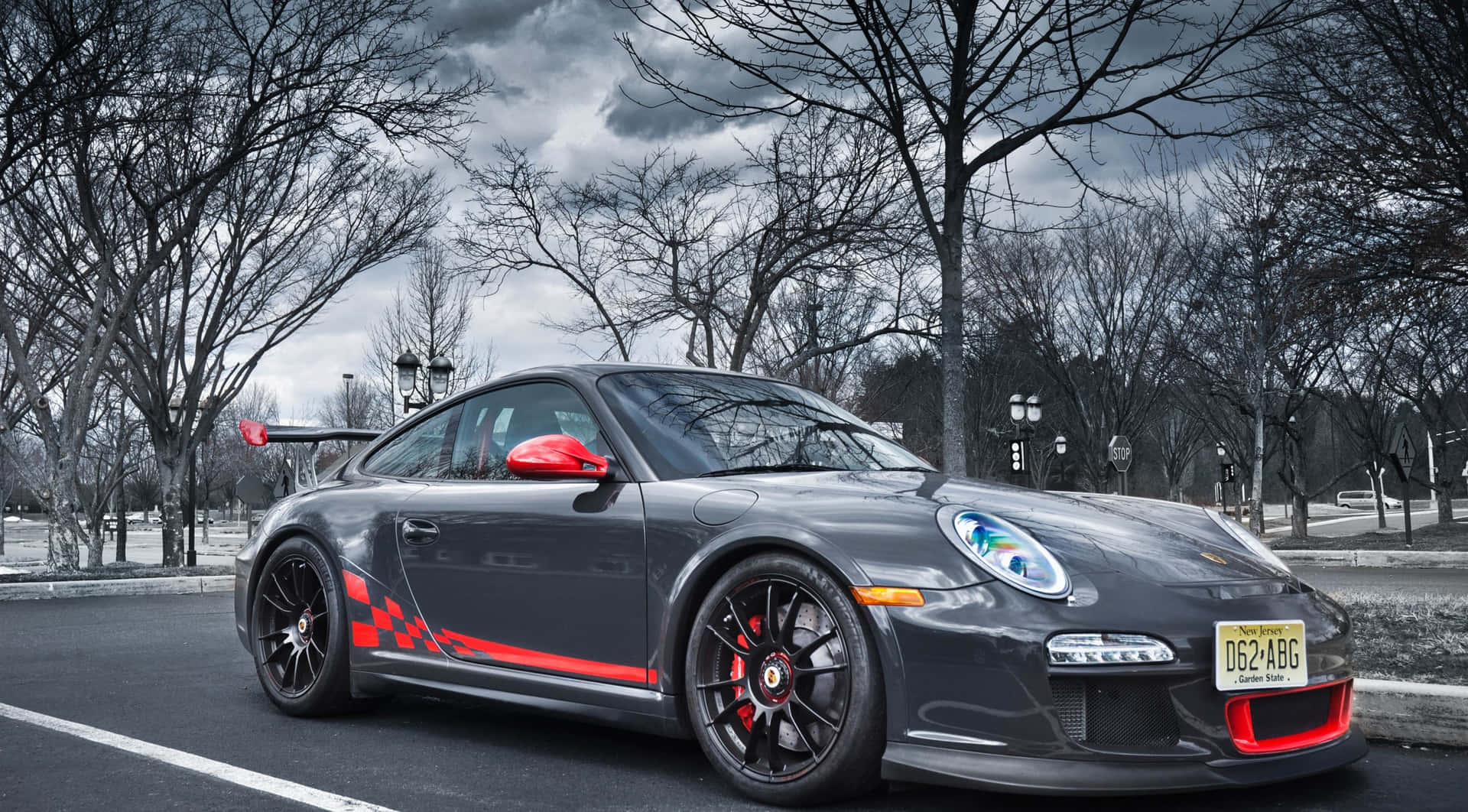灰色保時捷911 GT3 RS，帶紅色點綴，停在光禿樹木和陰天下的街道上。