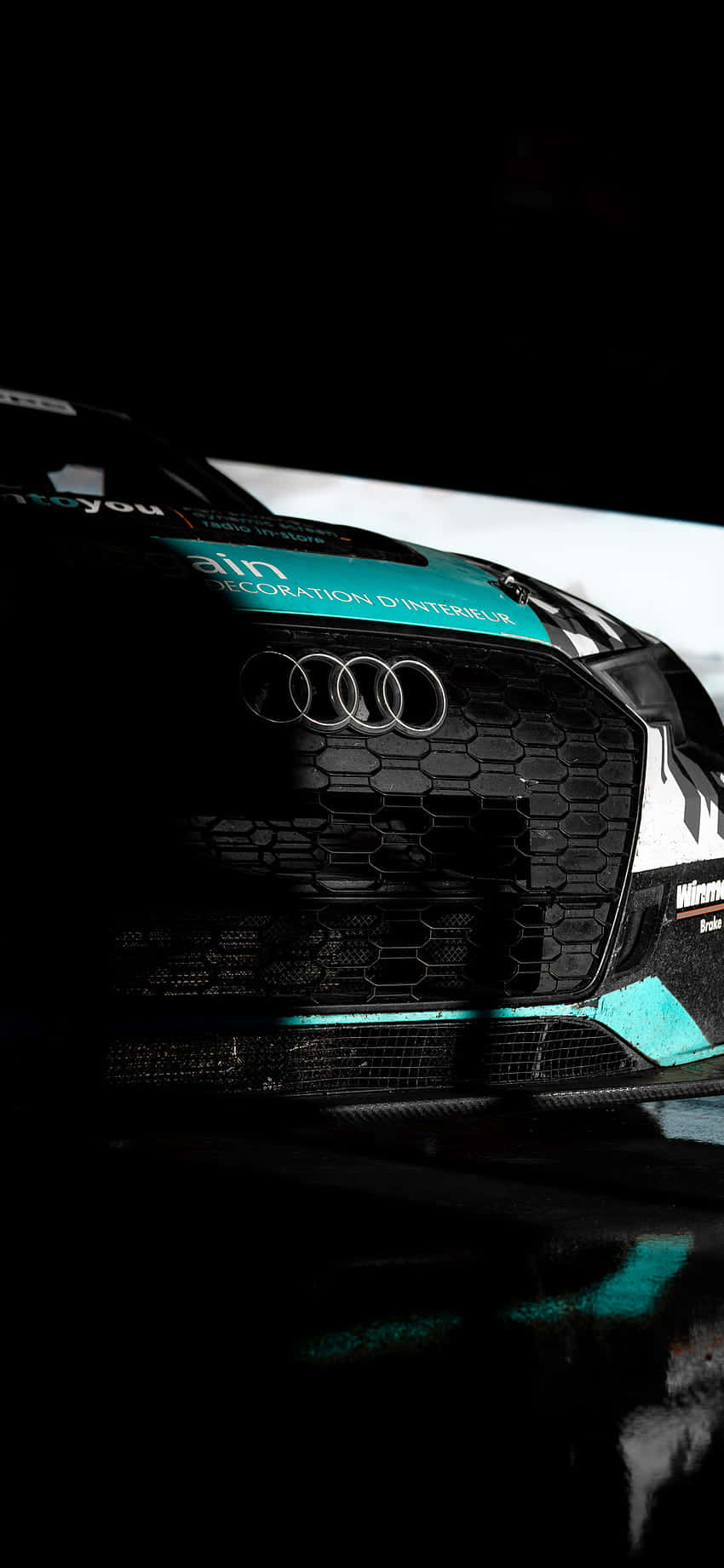 Audi 賽車前格柵特寫，帶有青綠色點綴和碳纖維紋理。