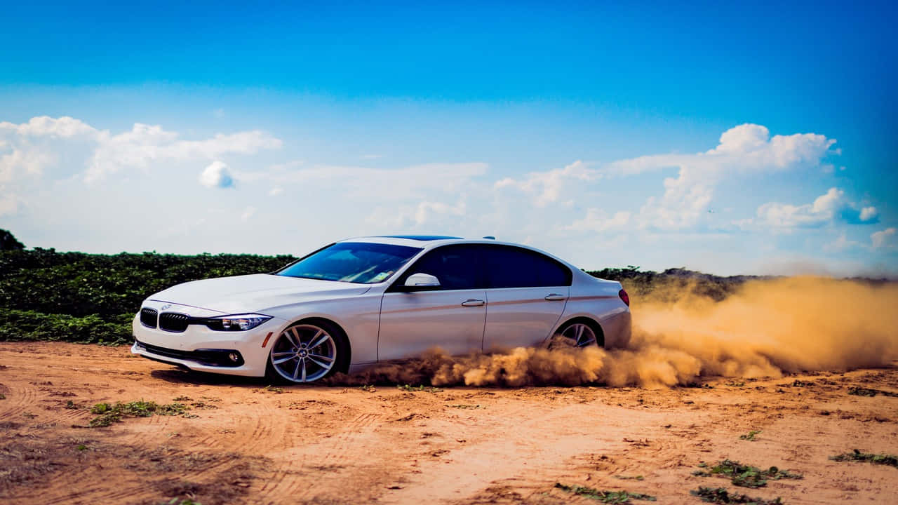 駕馭豪華 BMW，享受時尚駕馭體驗 壁紙 — 一輛白色BMW房車在晴朗藍天白雲下，於乾燥泥地上高速行駛，揚起塵土。