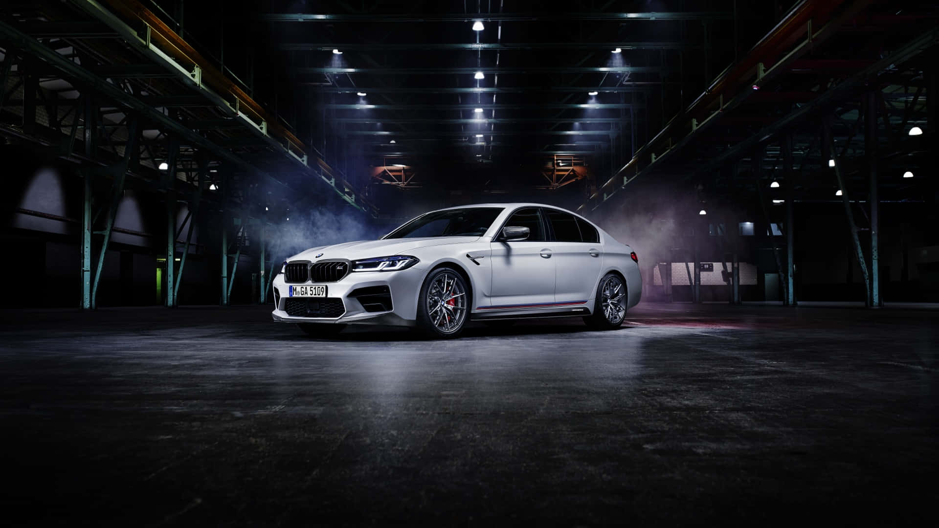 白色BMW M5房車在黑暗的工業倉庫中，帶有煙霧和聚光燈。