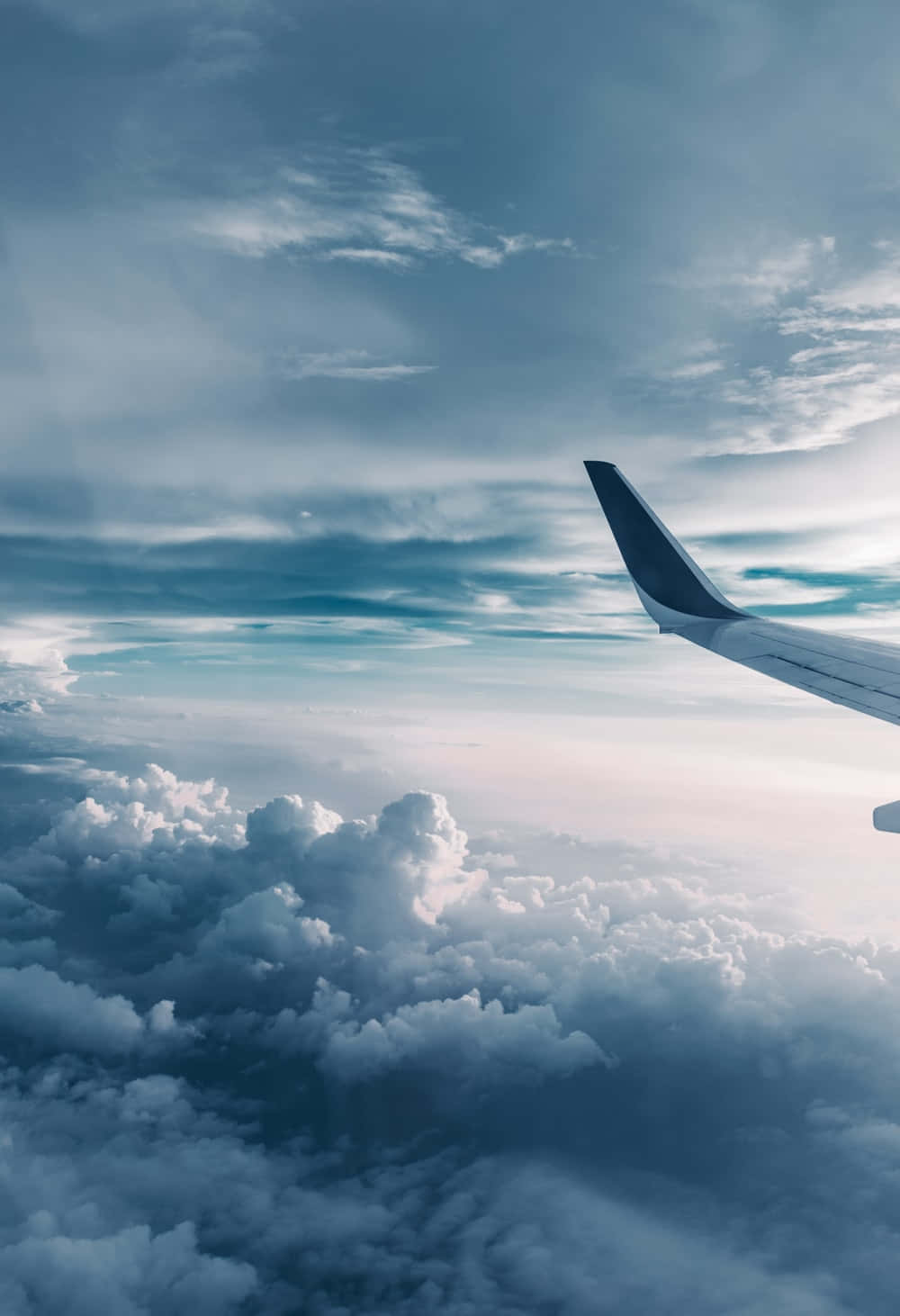 駕馭雲端 壁紙 — 飛機機翼延伸在蓬鬆白雲的海洋之上，下方是廣闊的藍天和纖細的卷雲。