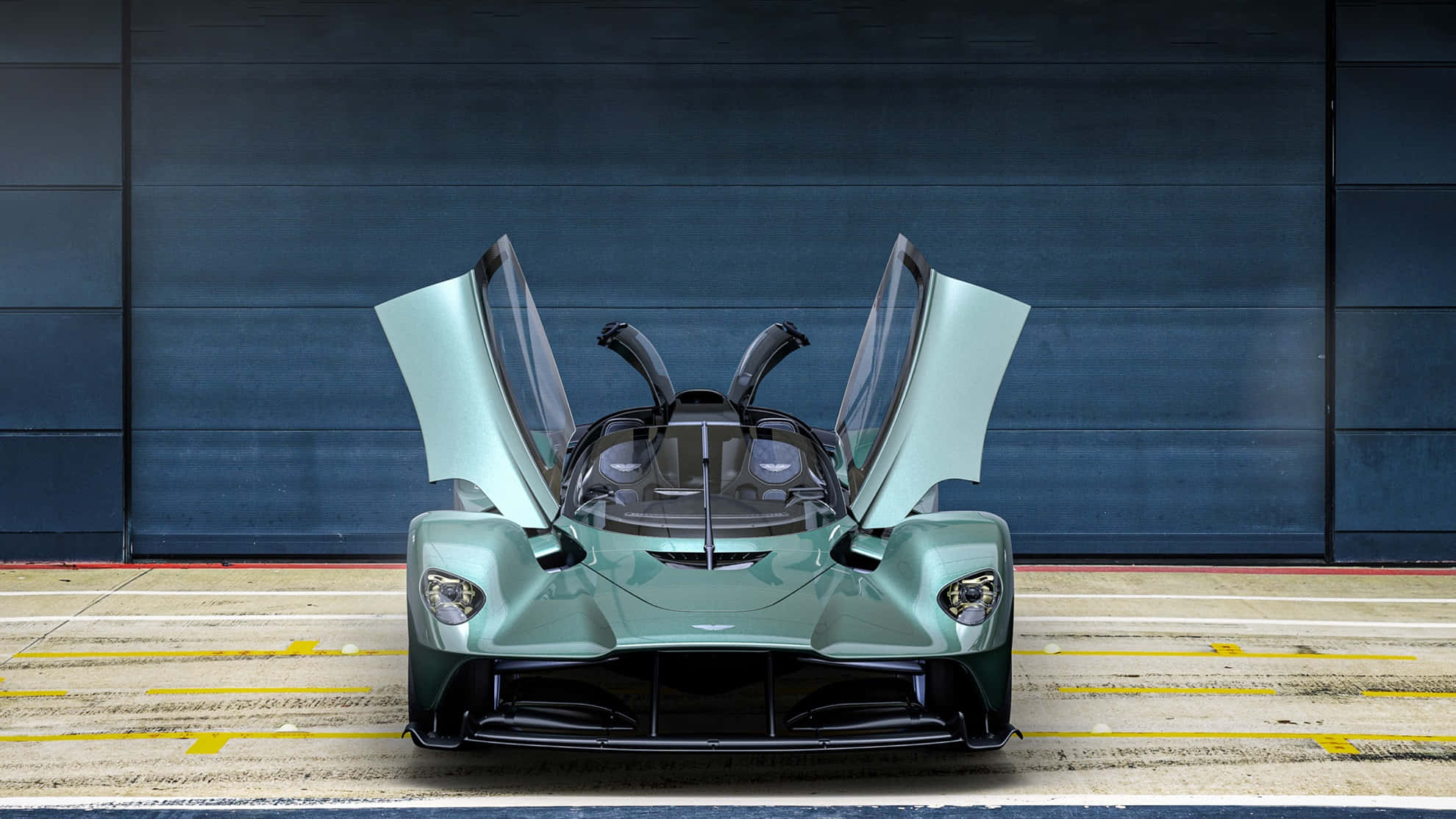 駕駛 Aston Martin，享受奢華 壁紙 — 一架流線型薄荷綠色超跑，鷗翼門打開，停在深藍色車庫門前，地面是帶標記的混凝土。