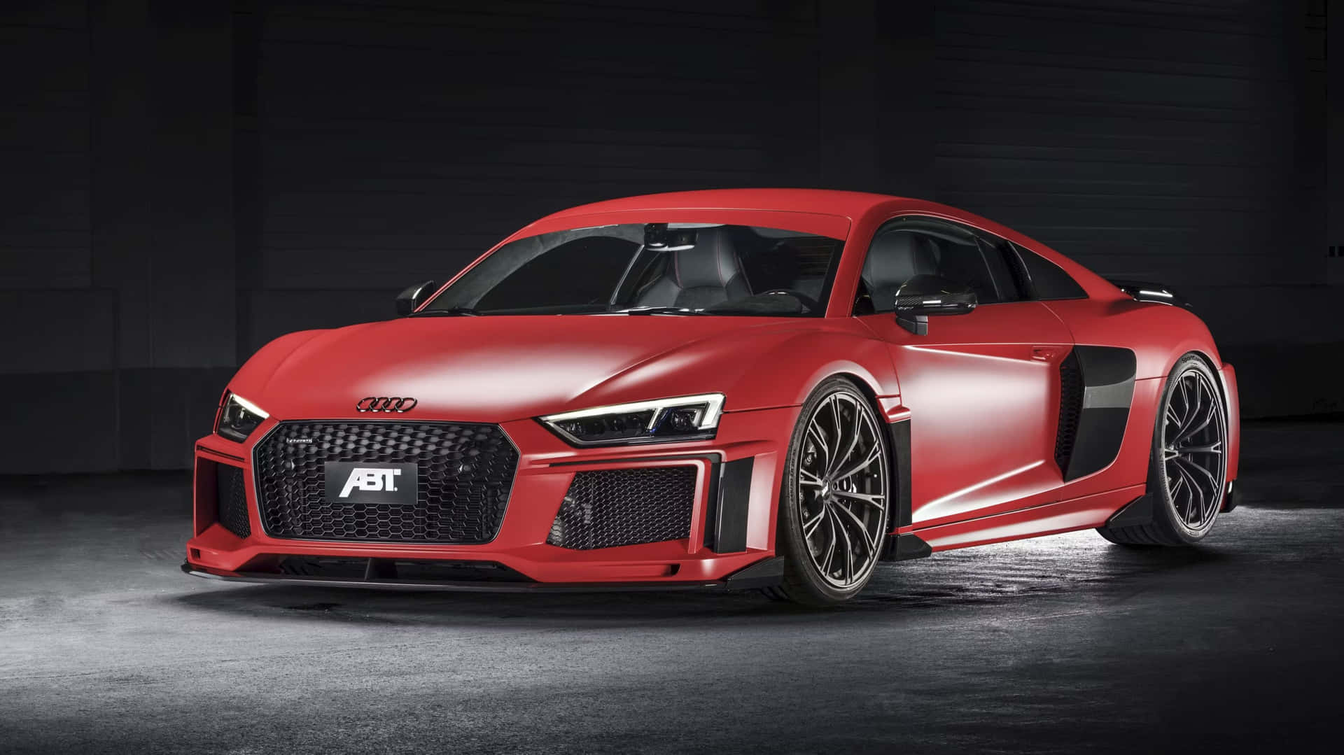 啞光紅色ABT Audi R8跑車在黑暗車庫中，聚光燈照射。
