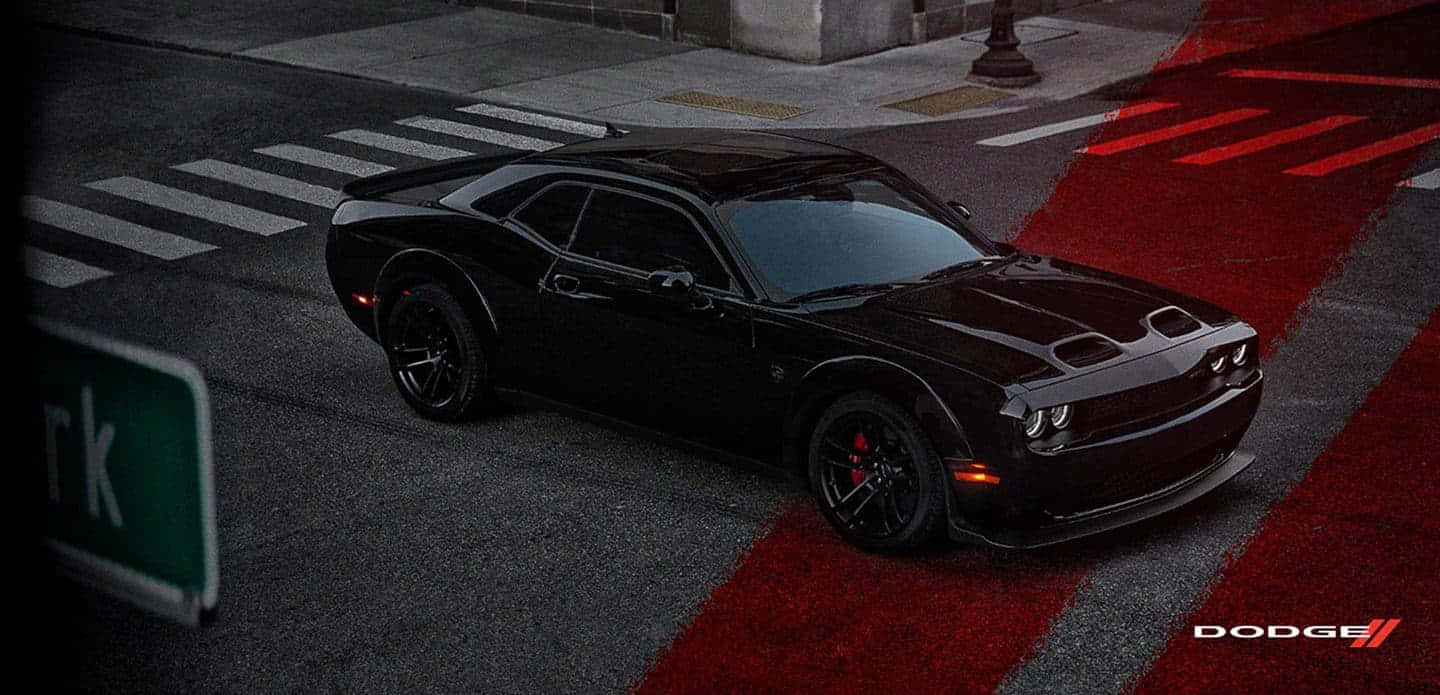 夜間在紅色條紋城市街道上的黑色 Dodge Challenger。