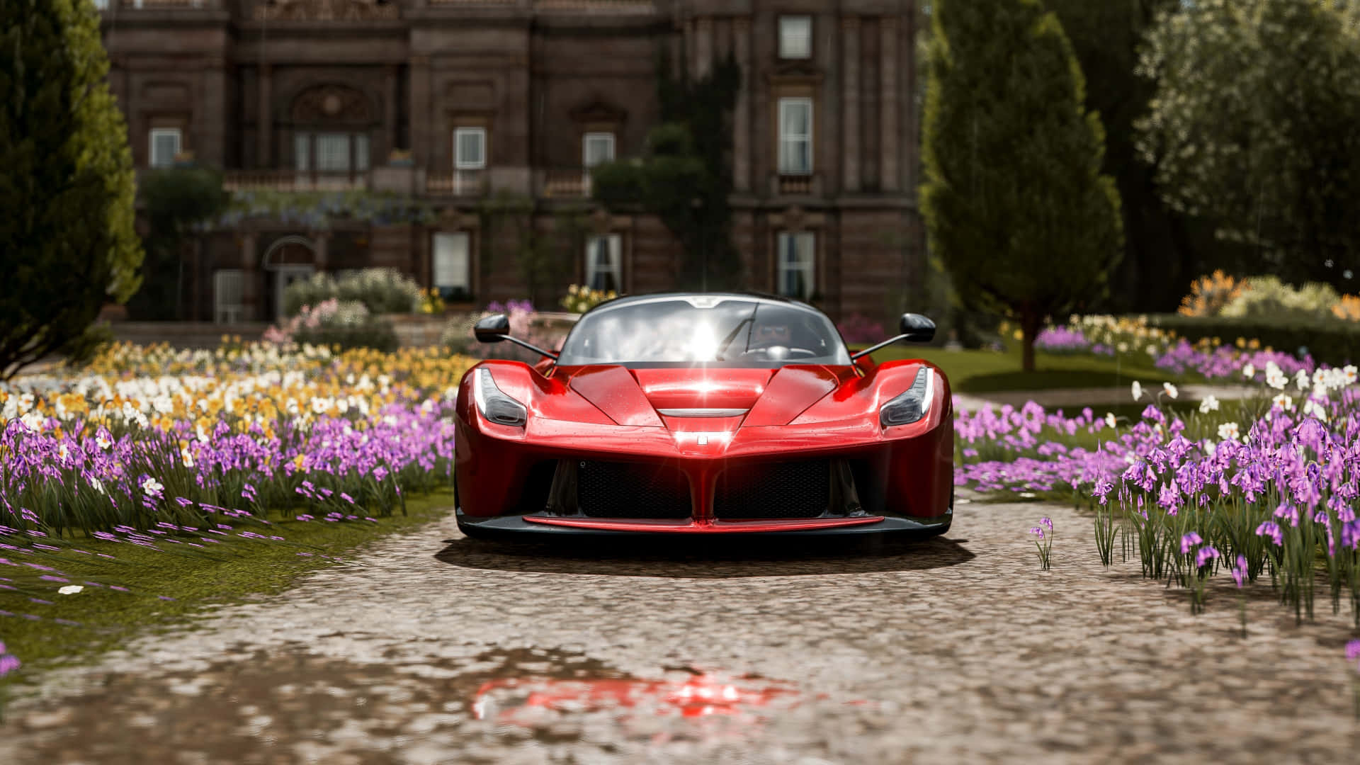 駕駛《Forza Horizon 4》的公路 壁紙 — 一架亮麗的紅色跑車停泊在濕漉漉的鵝卵石小徑上，周圍環繞著鮮豔的紫色和黃色花朵，背景是一座宏偉的大宅。