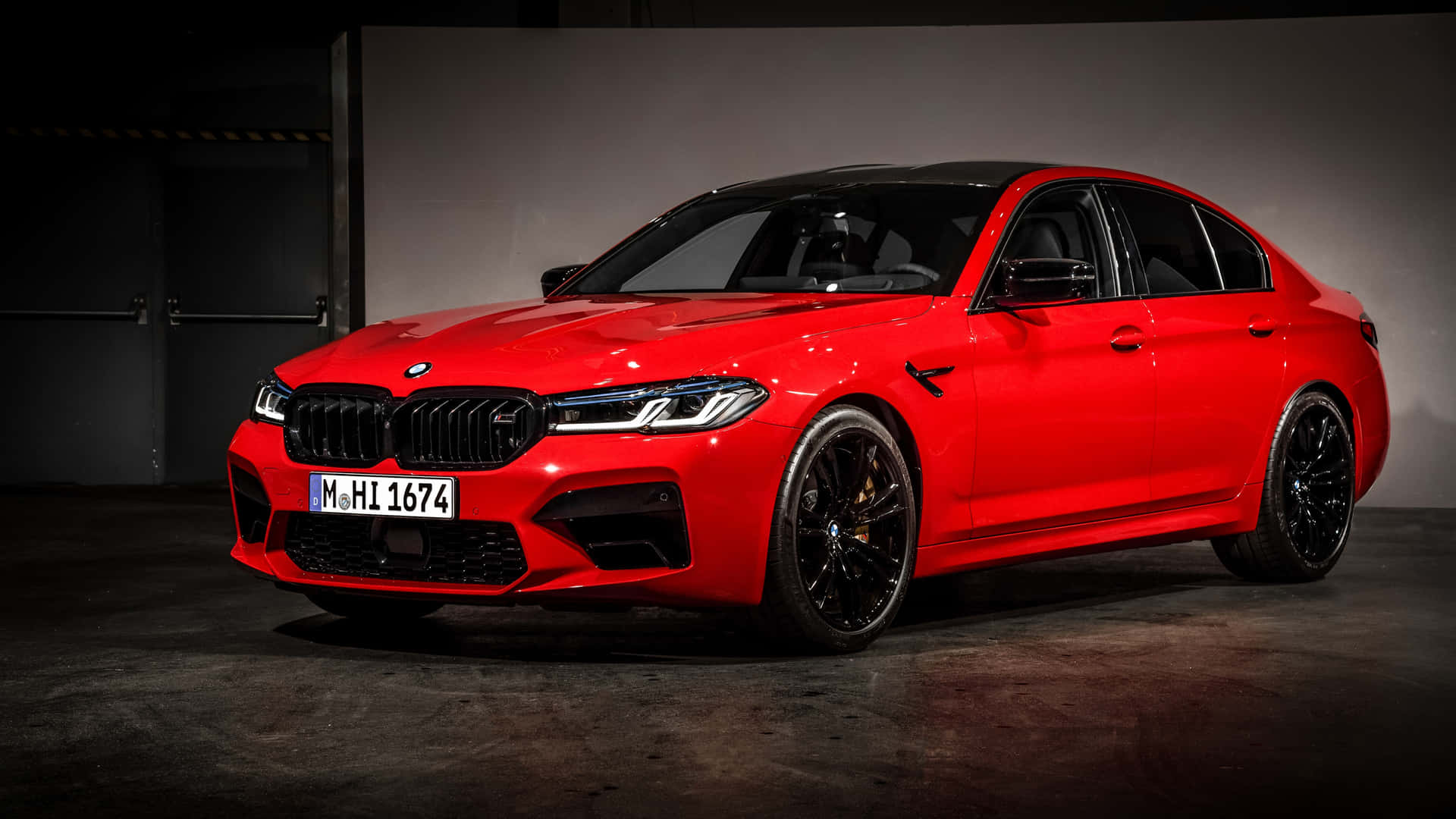 紅色BMW M5房車停放在昏暗的車庫中，配備黑色輪圈和明亮的車頭燈。