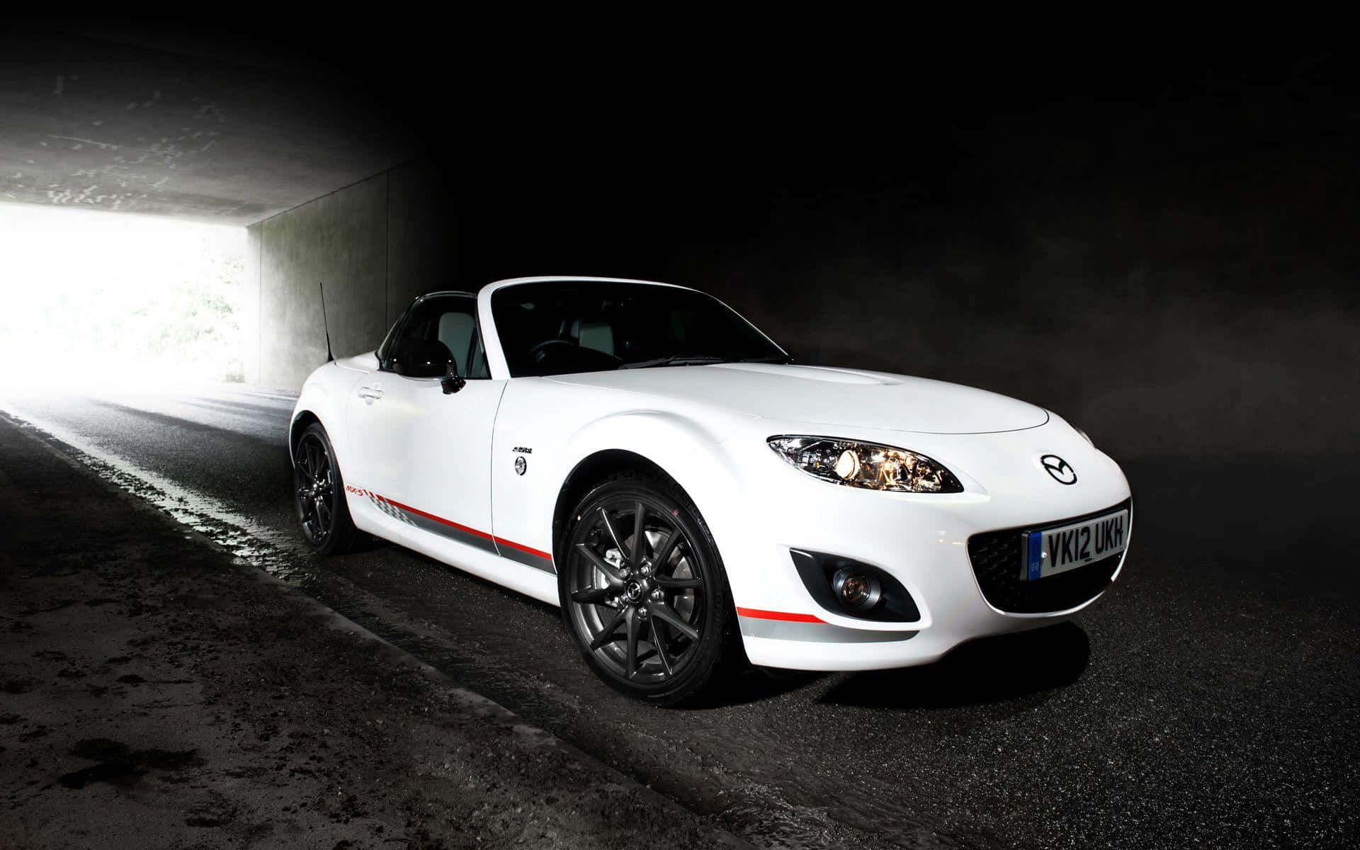 白色Mazda MX-5開篷跑車駛出黑暗隧道進入明亮光線。