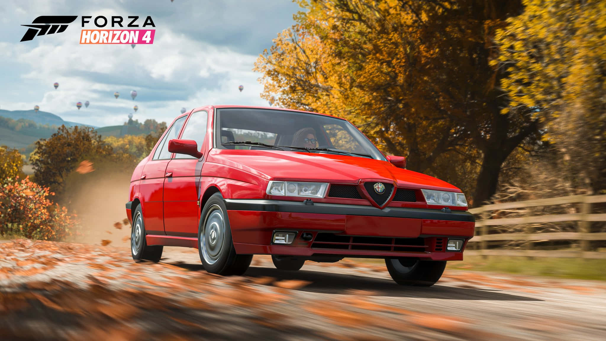 駕駛Alfa Romeo，享受旅程 壁紙 — 一輛鮮紅色的阿爾法羅密歐轎車在金色的秋林中飛馳，天空中飄浮著熱氣球。