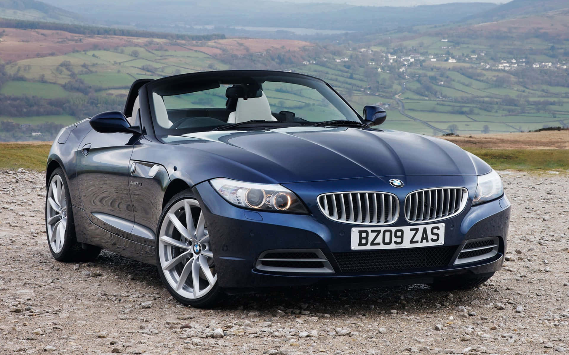 深藍色BMW Z4開篷跑車停泊在風景優美的山坡上，俯瞰著景色。