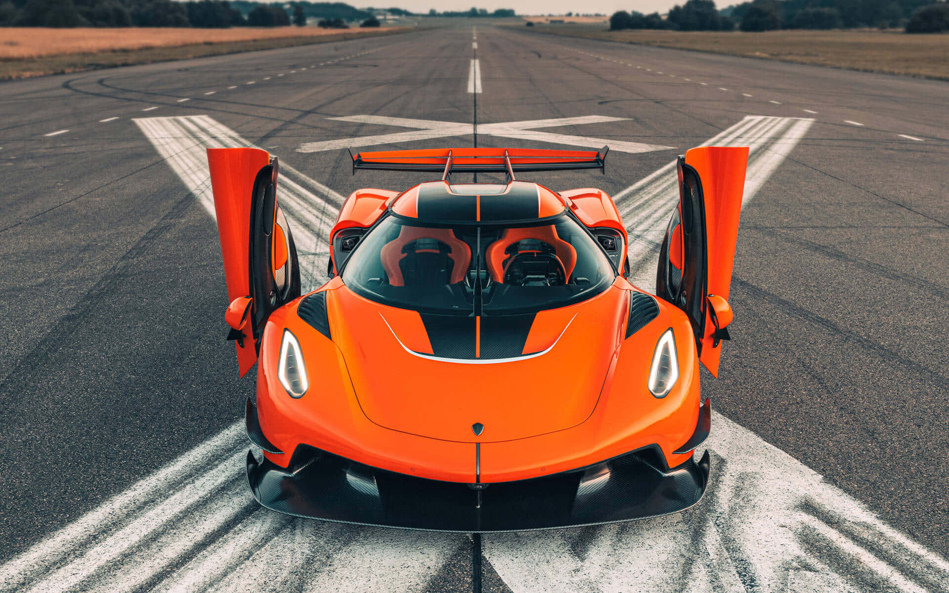 橙色Koenigsegg超跑喺機場跑道打開車門。