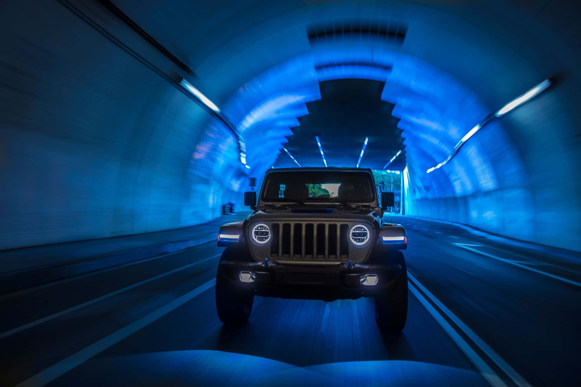 黑色Jeep Wrangler在夜間於藍色燈光隧道中高速行駛。