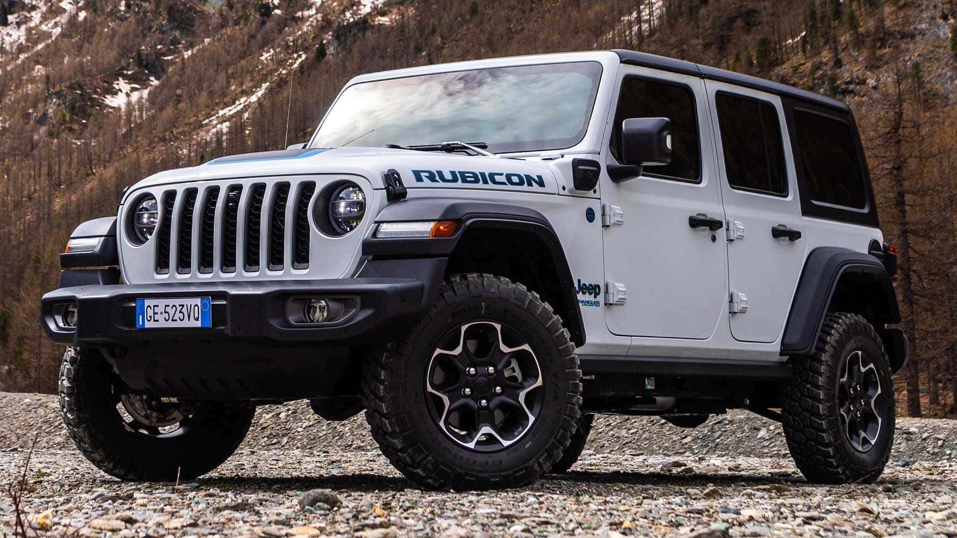 白色Jeep Rubicon停放在靠近雪山的多岩石地形上。