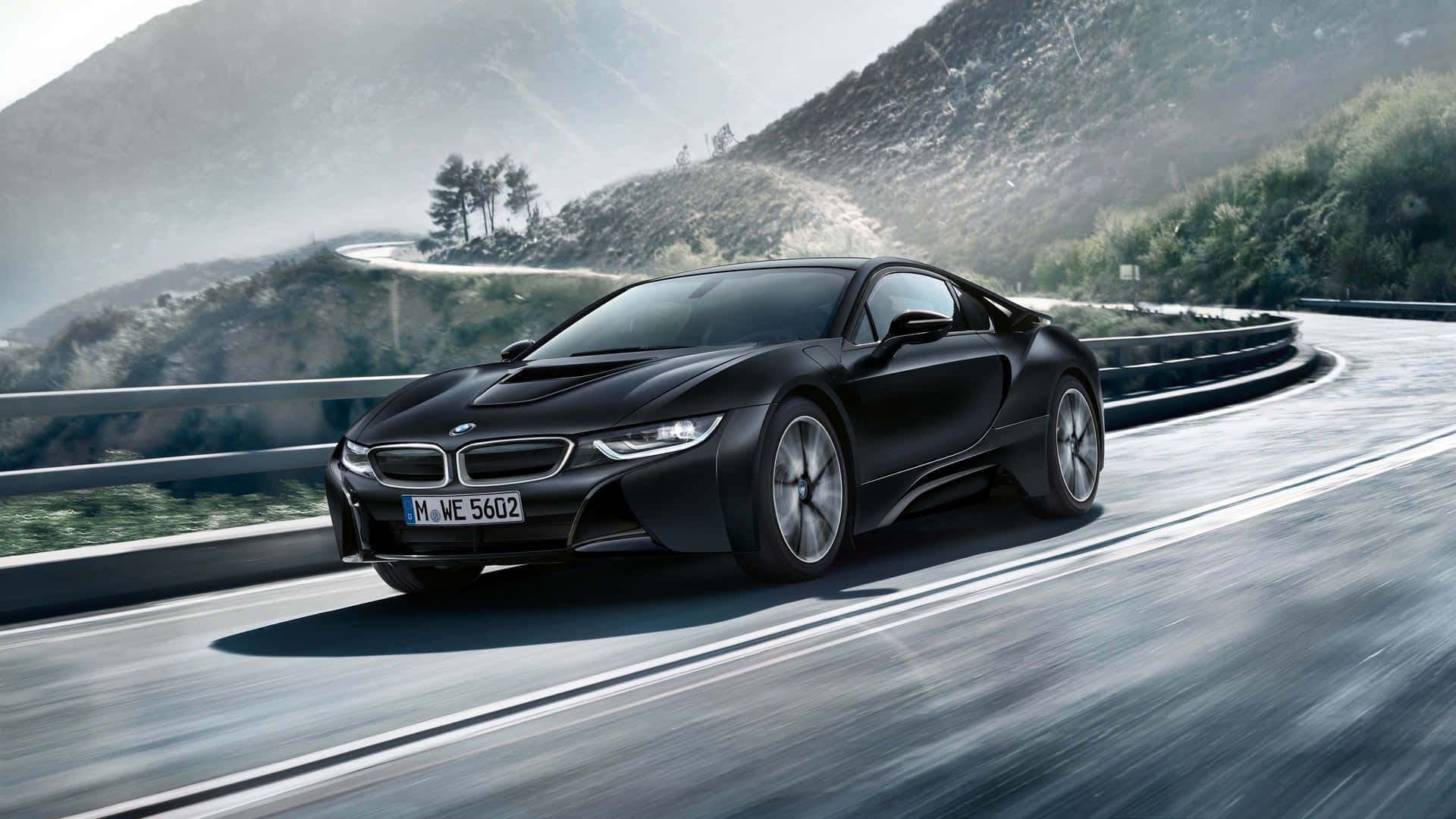 黑色BMW i8在山路上高速行駛，帶有模糊動感和霧氣繚繞的山丘。