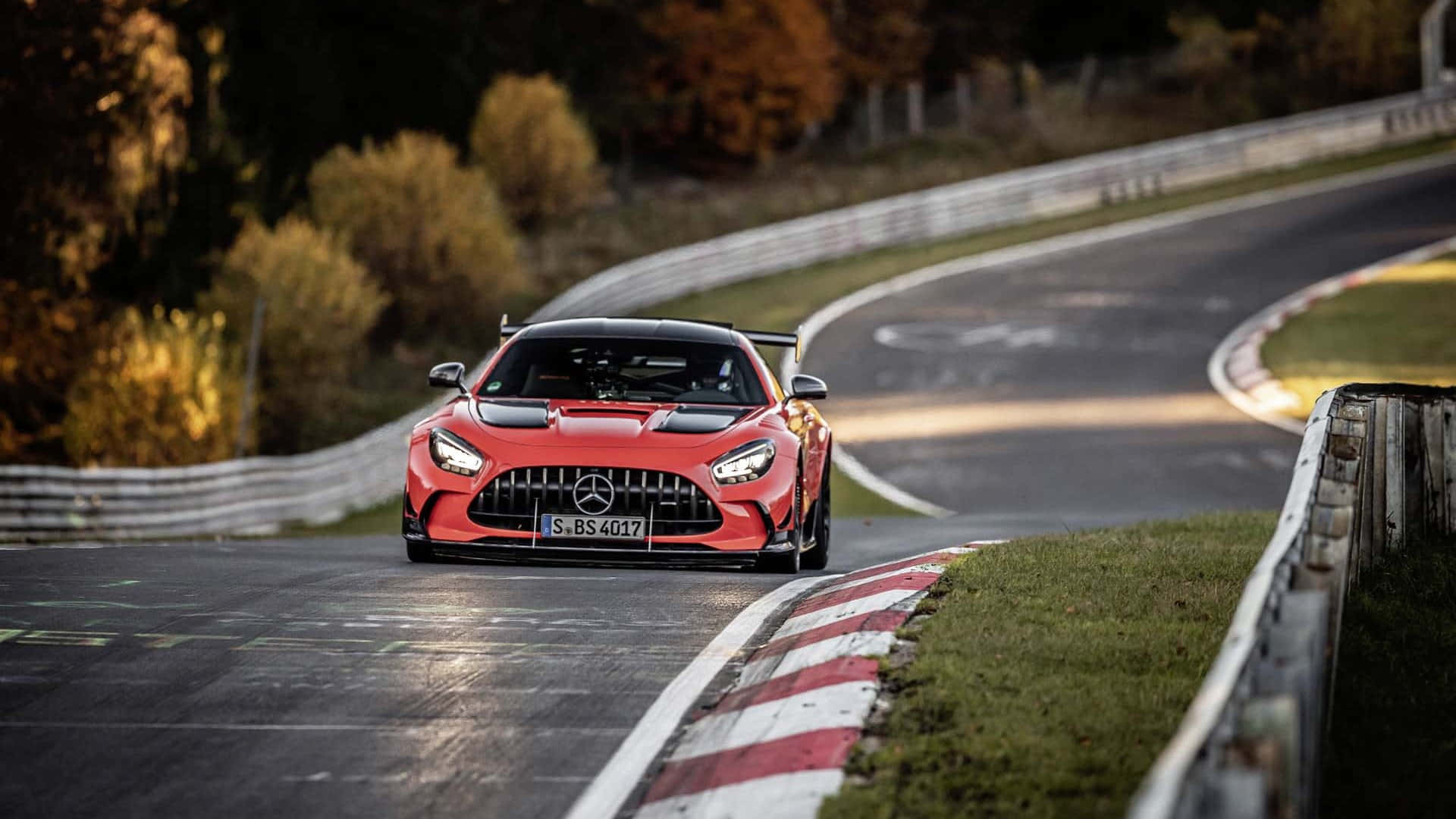 紅色 Mercedes-AMG GT R 賽車在蜿蜒的賽道上，背景有秋樹和日落光線。