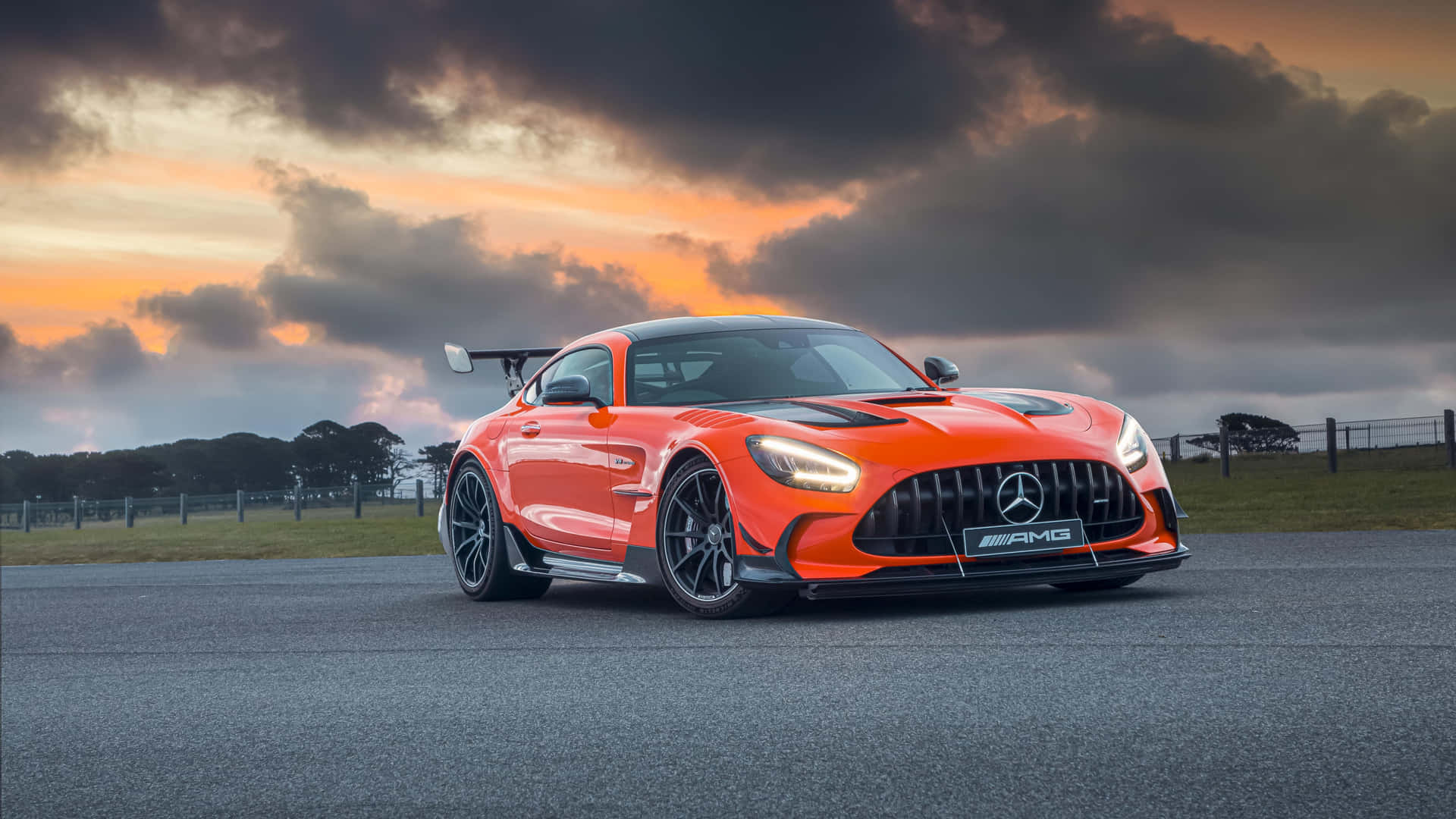 日落時分賽道上的橙色Mercedes-AMG GT R與戲劇性的雲層。