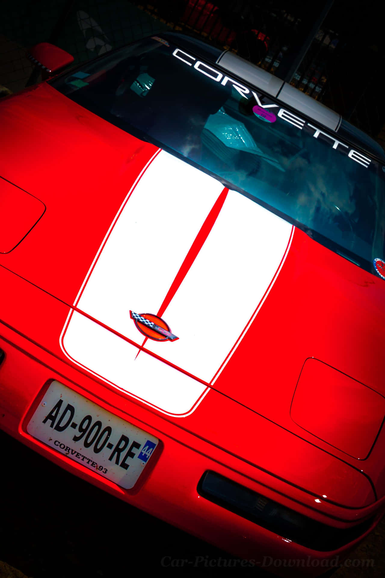 夜間燈光下帶有白色條紋的紅色Corvette跑車。