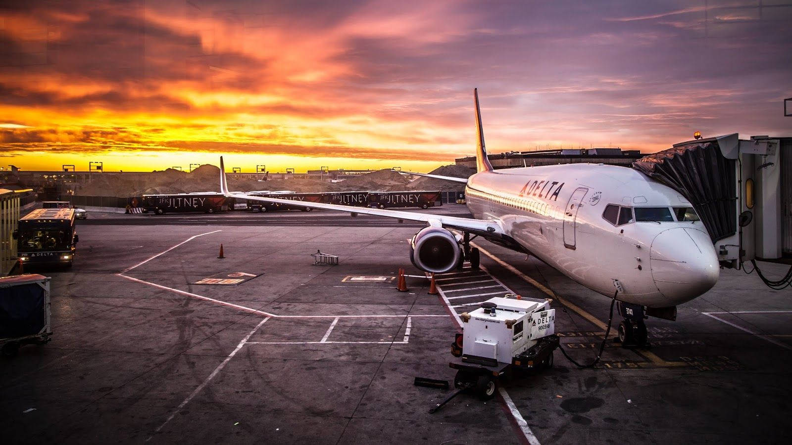 達美航空飛機在機場閘口，日落色彩鮮豔。