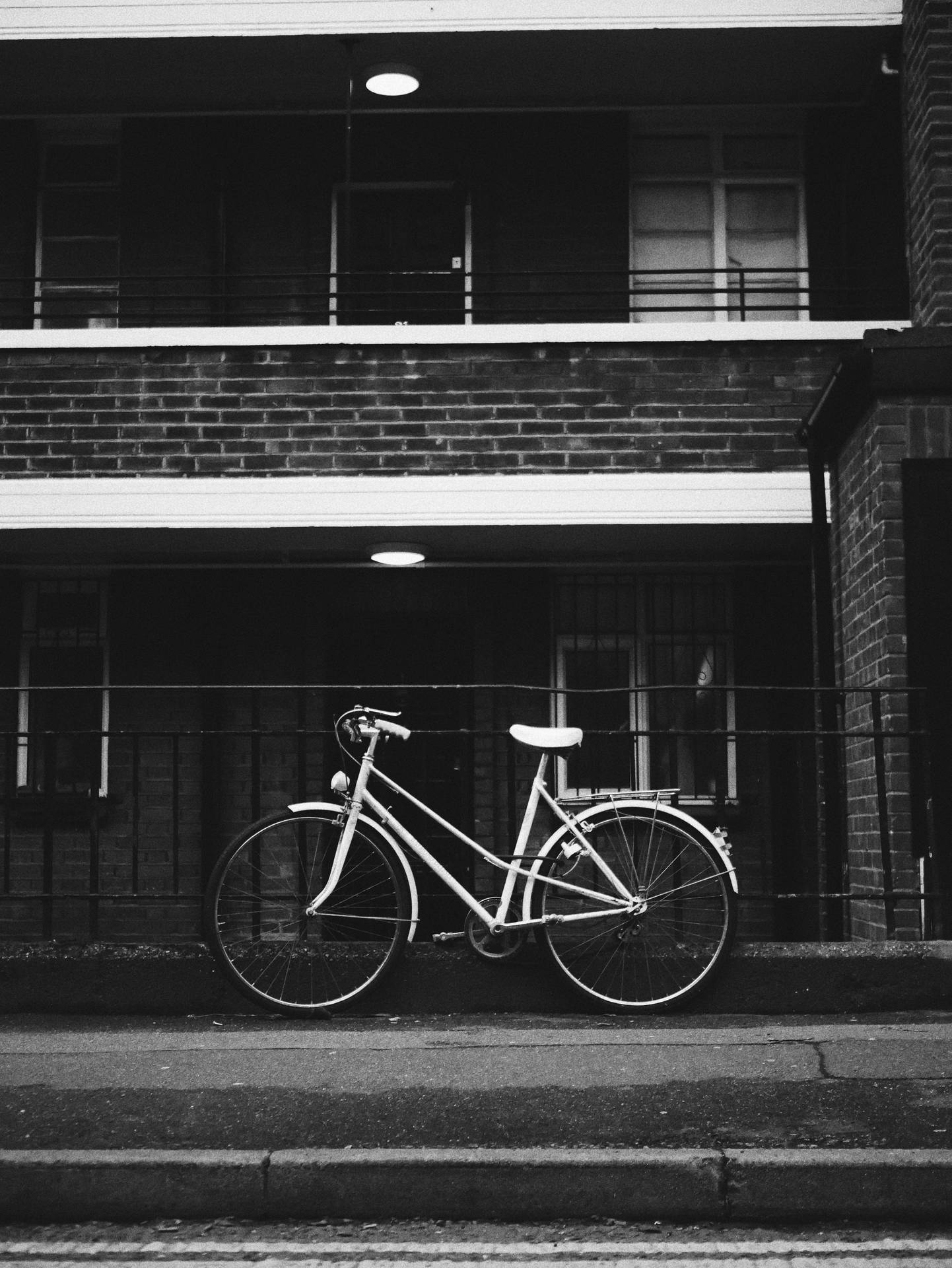 一輛經典單車在夜間停靠在磚砌建築旁。