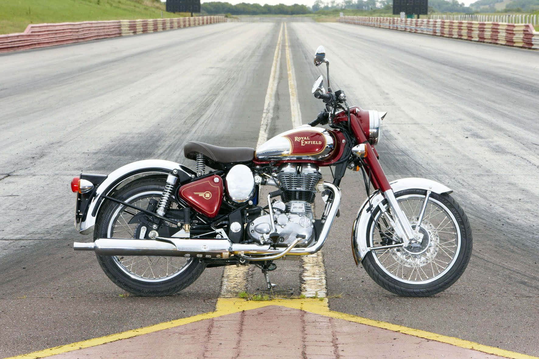 復古紅色 Royal Enfield 電單車停在賽車場起跑線上。