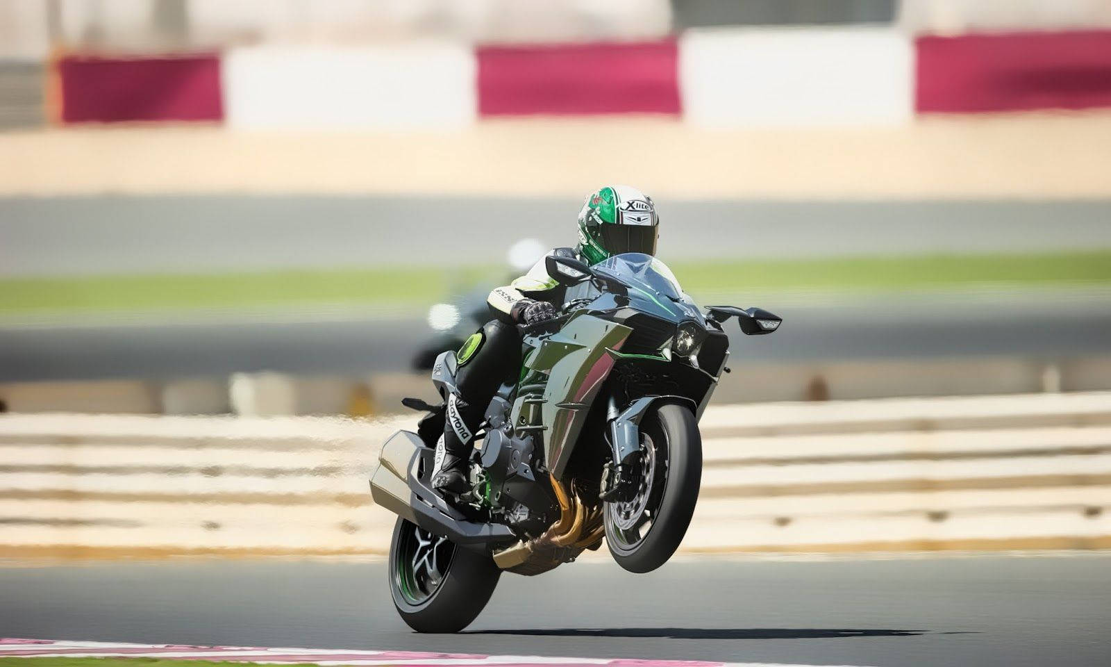 騎士駕駛 Kawasaki H2r 焦點特寫 壁紙 — 一名電單車手在賽道上高速過彎時，將其中一個輪胎離地，身體傾斜進行操作。