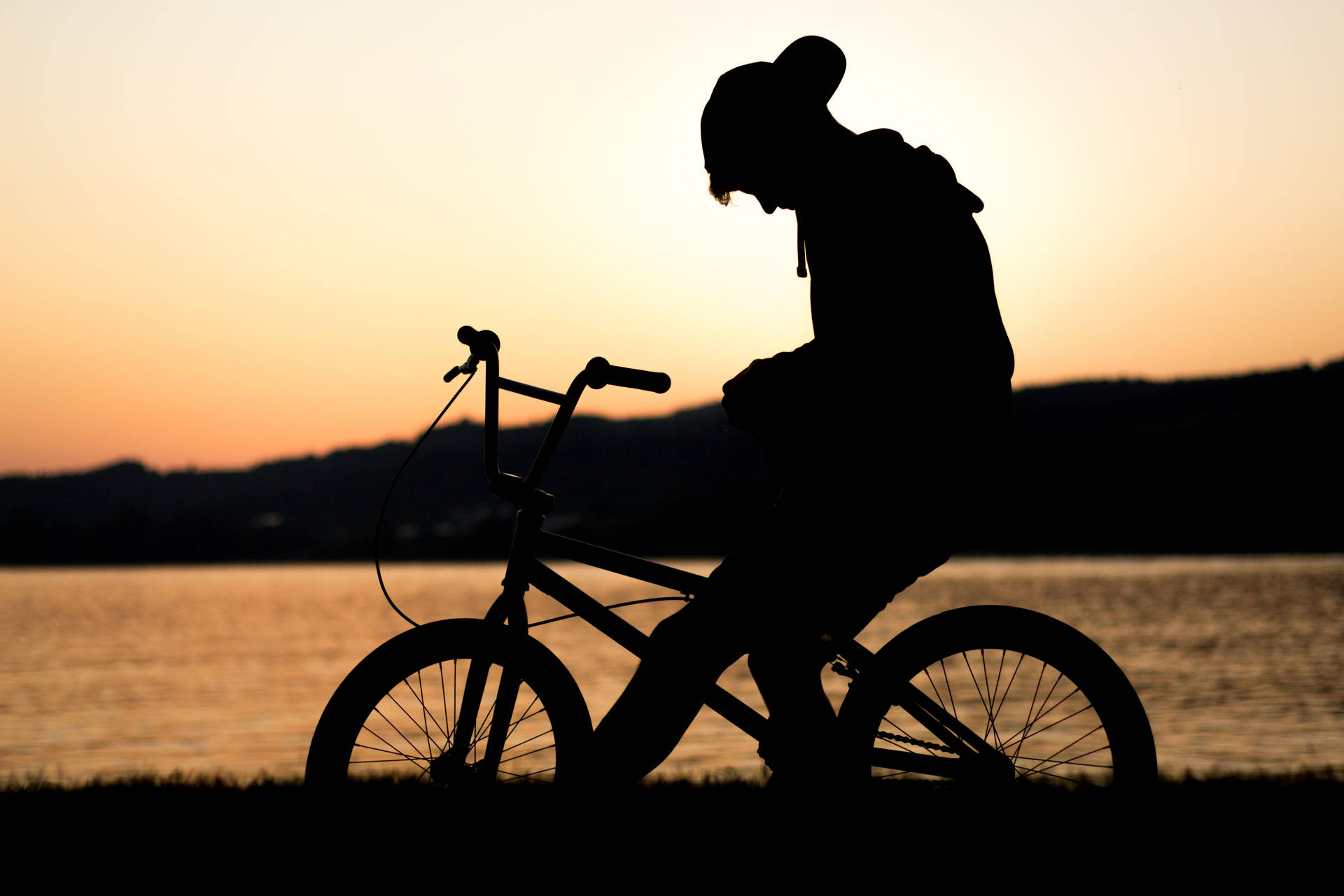 湖邊夕陽背景下騎單車的人的剪影