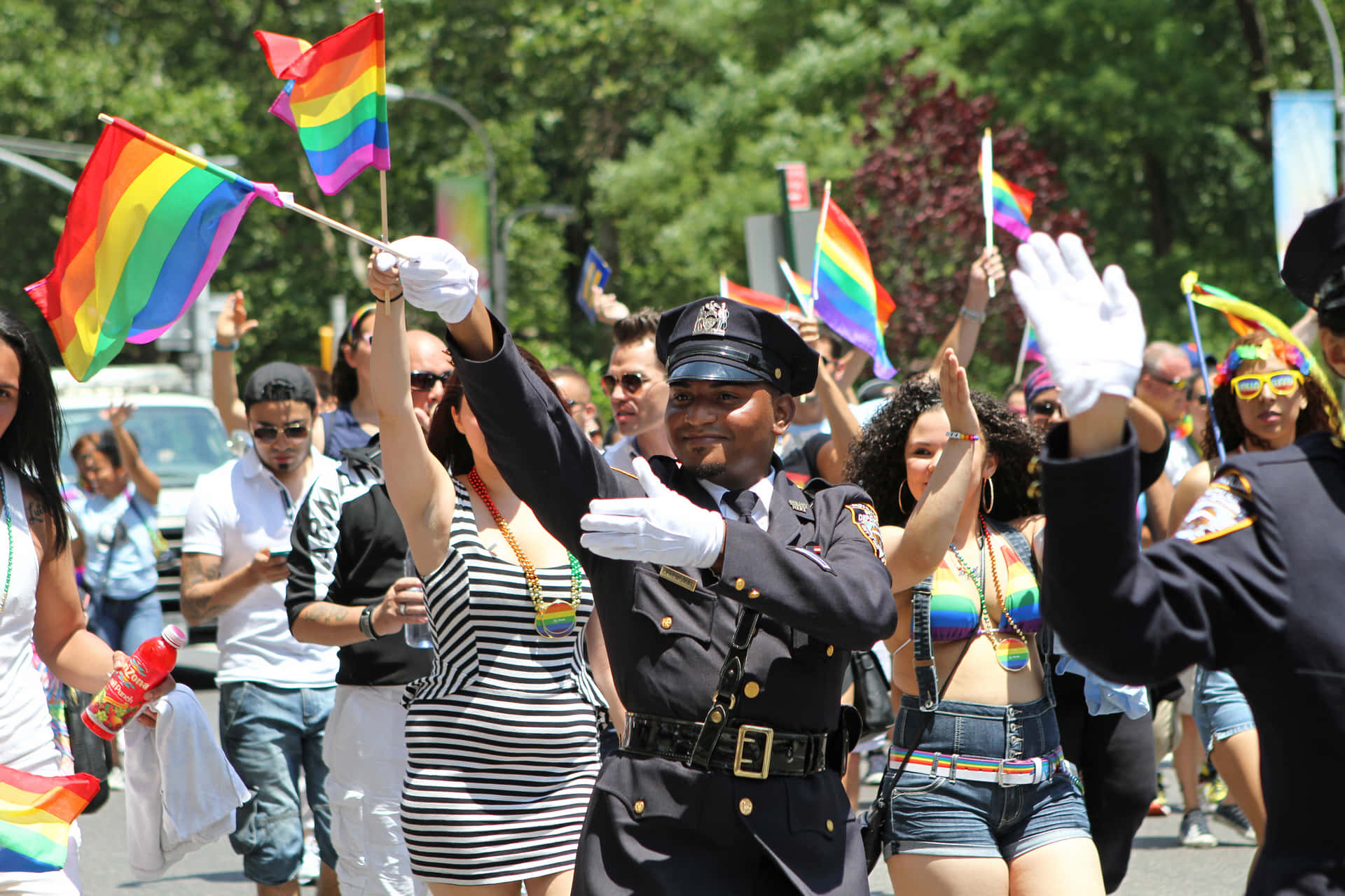 警察在Pride遊行中揮舞彩虹旗，微笑的人群。