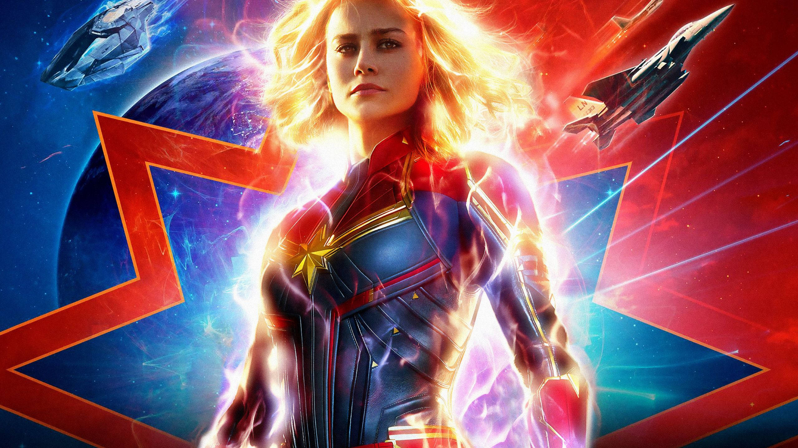 Captain Marvel Laptop 桌布 壁紙 — 驚奇隊長在宇宙場景中英勇站立，周圍有發光的能量效果和飛行的太空船。