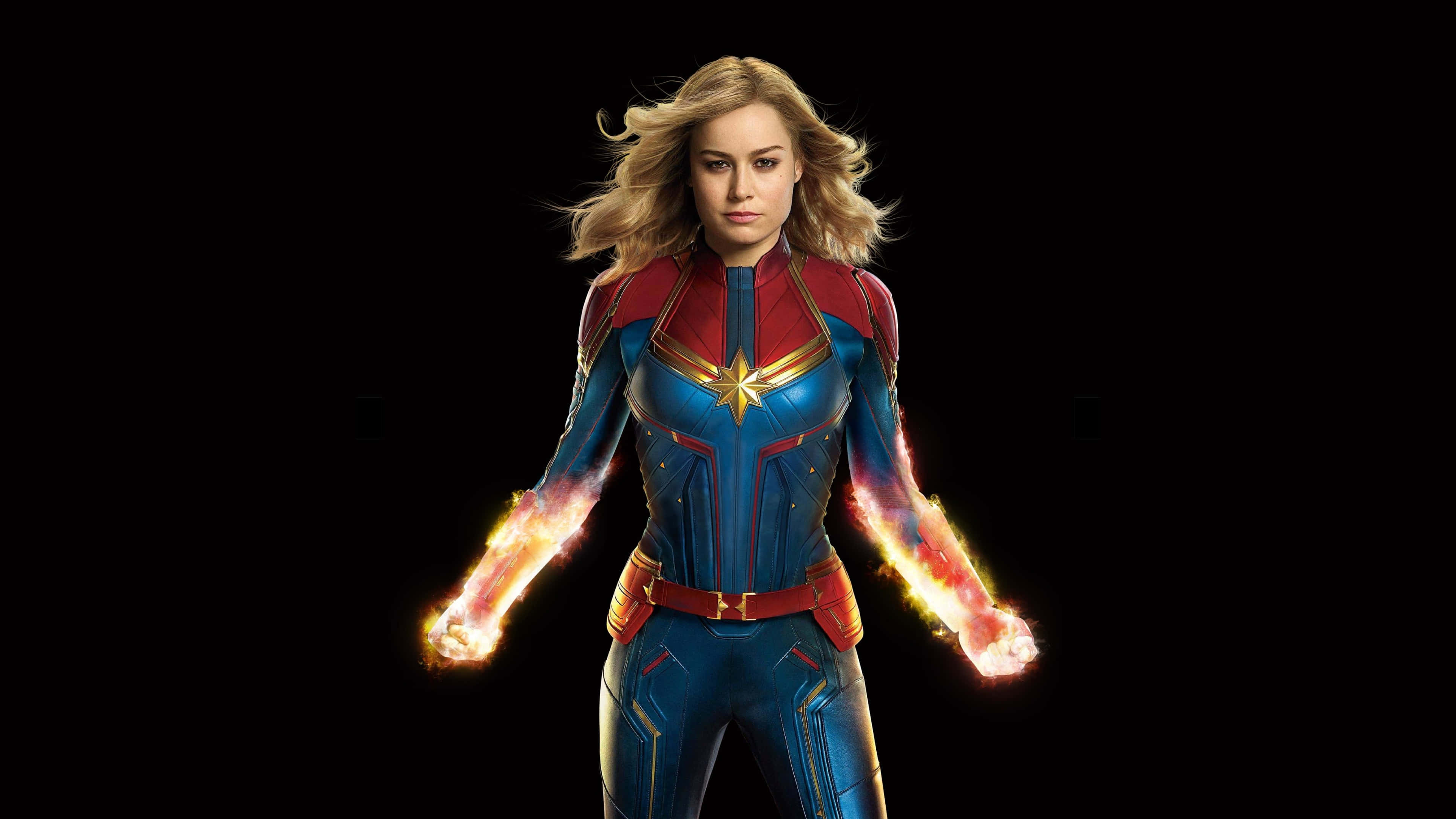 4K Marvel 壁紙 桌布 壁紙 — 驚奇隊長自信地站在黑色背景前，緊握的拳頭散發出發光的能量。