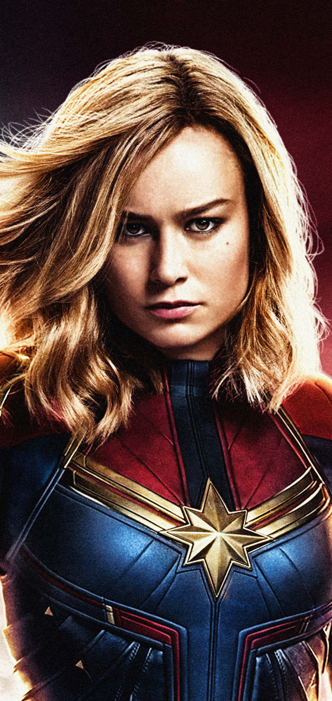 brie larson 桌布 壁紙 — 驚奇隊長身穿標誌性的藍紅戰衣，胸前有金色星星標誌，目光堅定地向前凝視。
