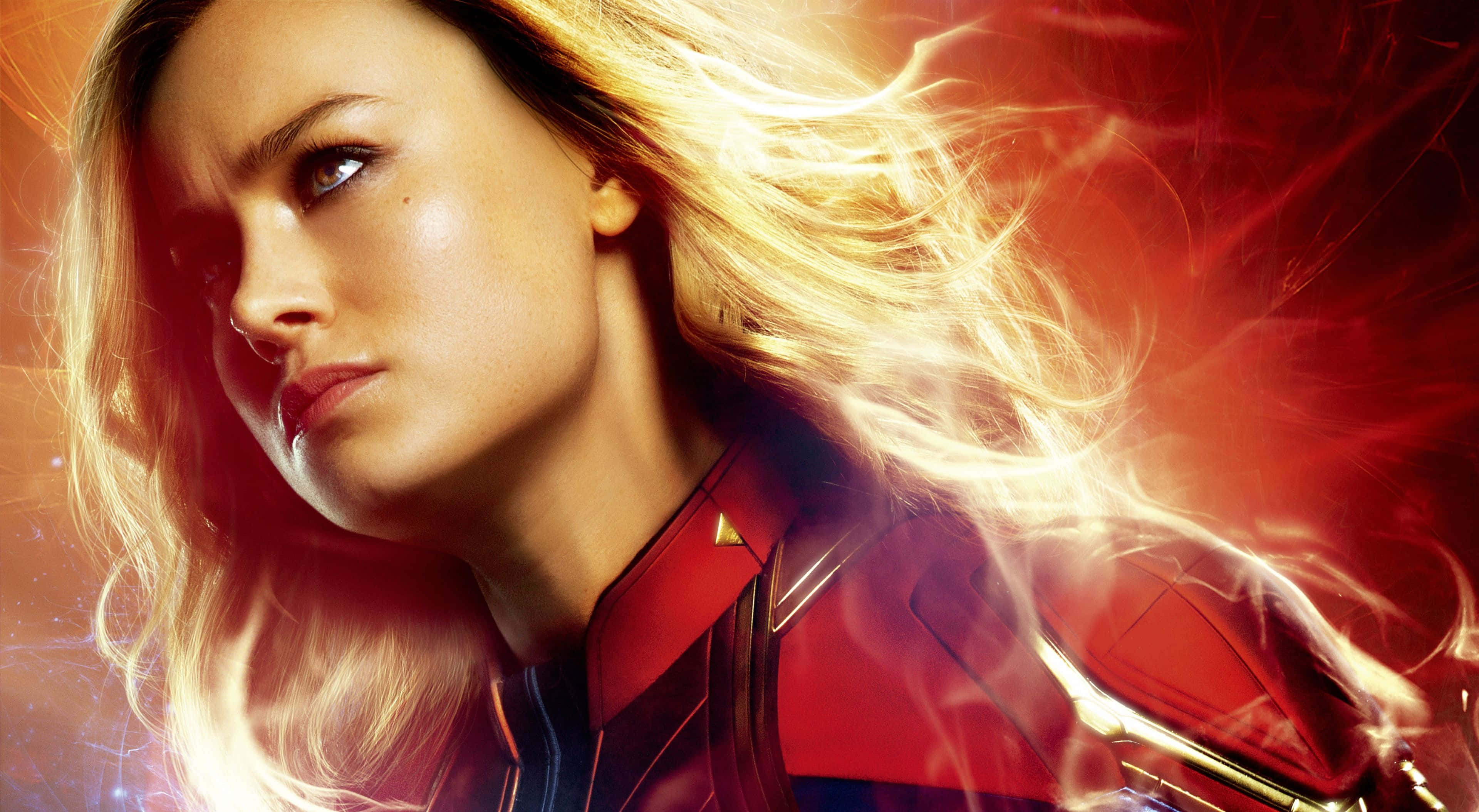 4K Marvel 壁紙 桌布 壁紙 — 驚奇隊長身穿紅色戰衣，散發著發光的能量，金色長髮飄逸，背景是宇宙。