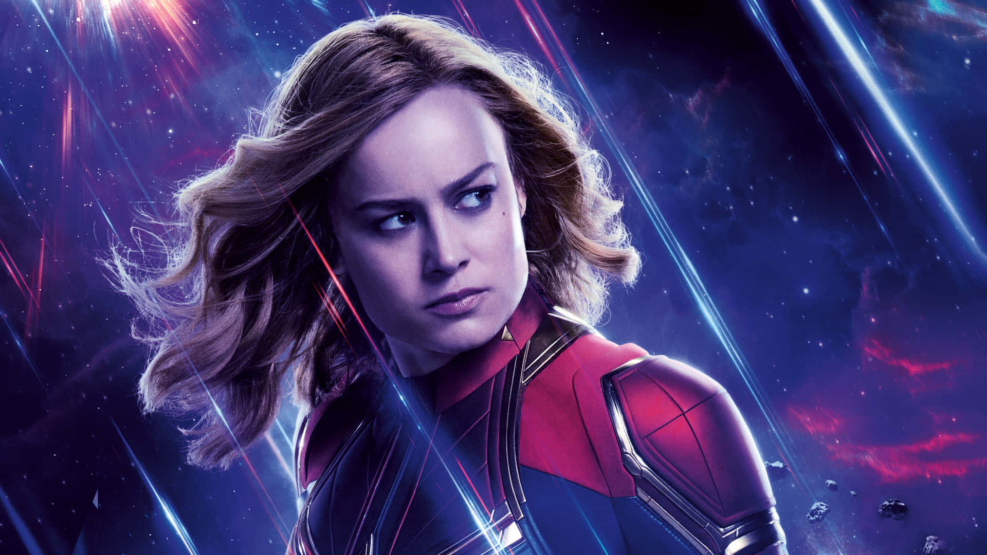 Captain Marvel HD 桌布 壁紙 — 驚奇隊長身穿紅藍戰衣，在充滿霓虹能量光束的鮮豔宇宙背景下堅定站立。