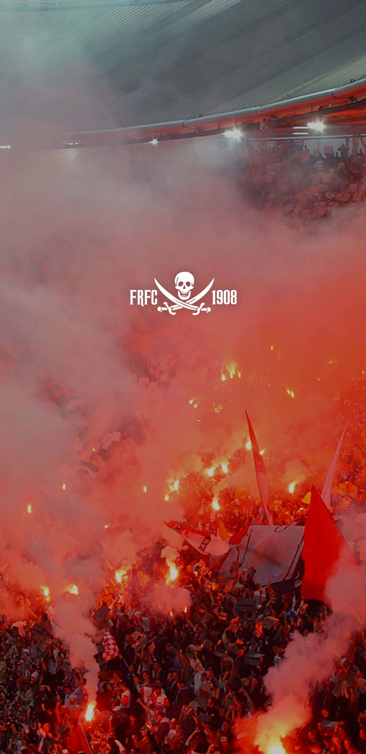 Feyenoord 桌布 壁紙 — 體育館人群在黑暗屋頂下爆發出火紅色的信號彈和煙霧，上方有骷髏標誌發光。