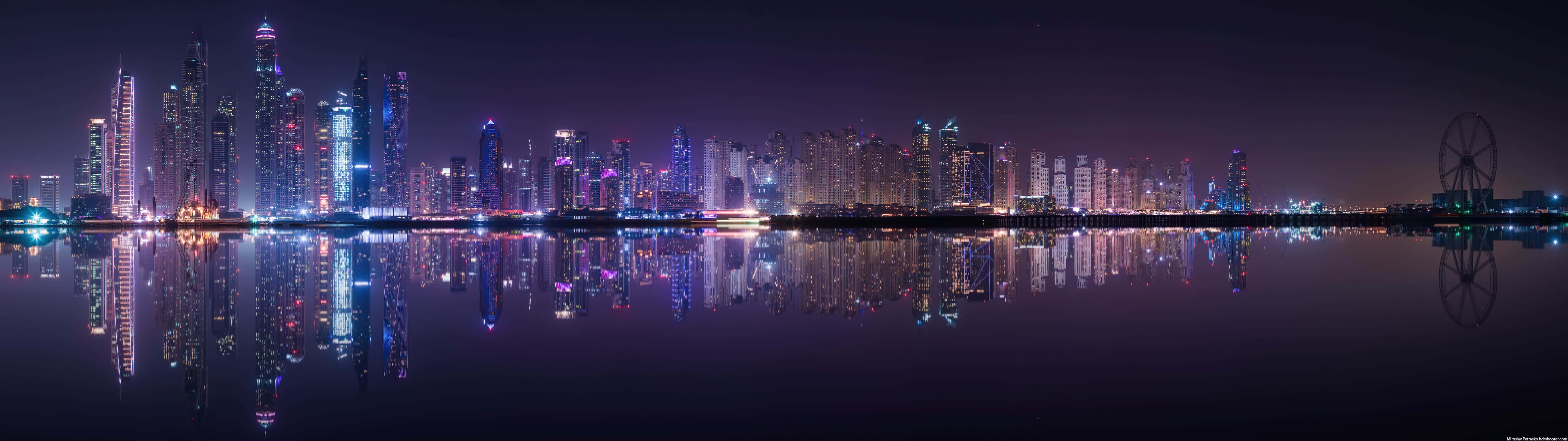 夜晚的杜拜天際線，摩天大樓和摩天輪倒映在水中。