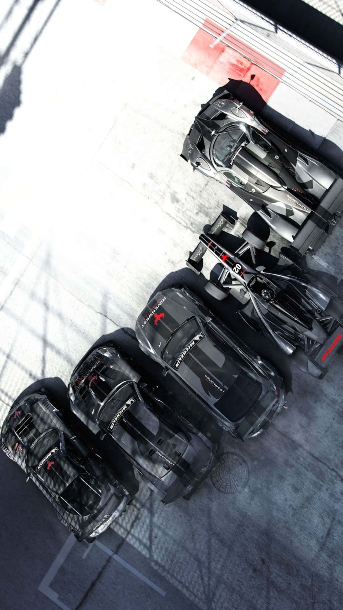 體驗 Android Grid Autosport 的賽車狂歡！ 壁紙 — 從上方俯瞰四輛時尚黑色賽車停放在帶有紅色和白色標記的混凝土車庫中。