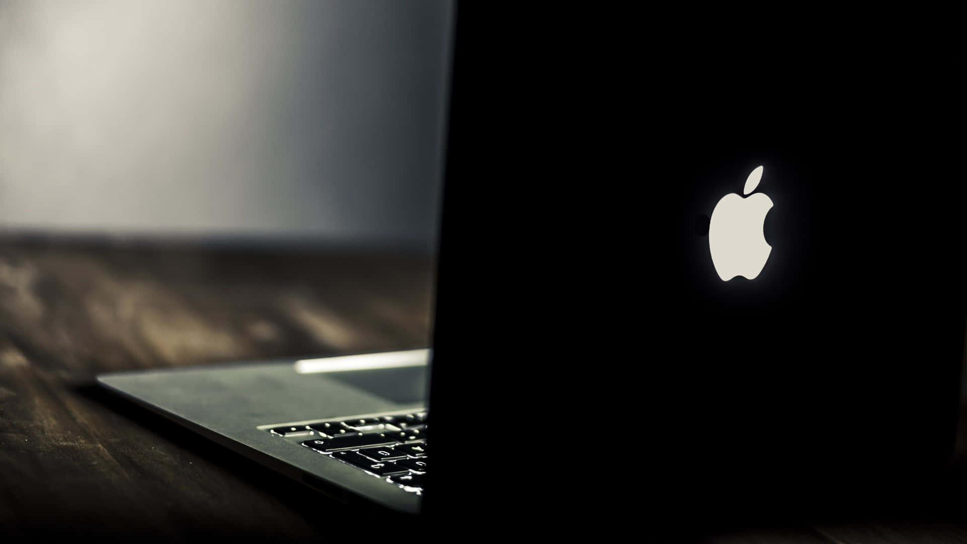 帶有發光Apple標誌的銀色手提電腦在深色木質表面上