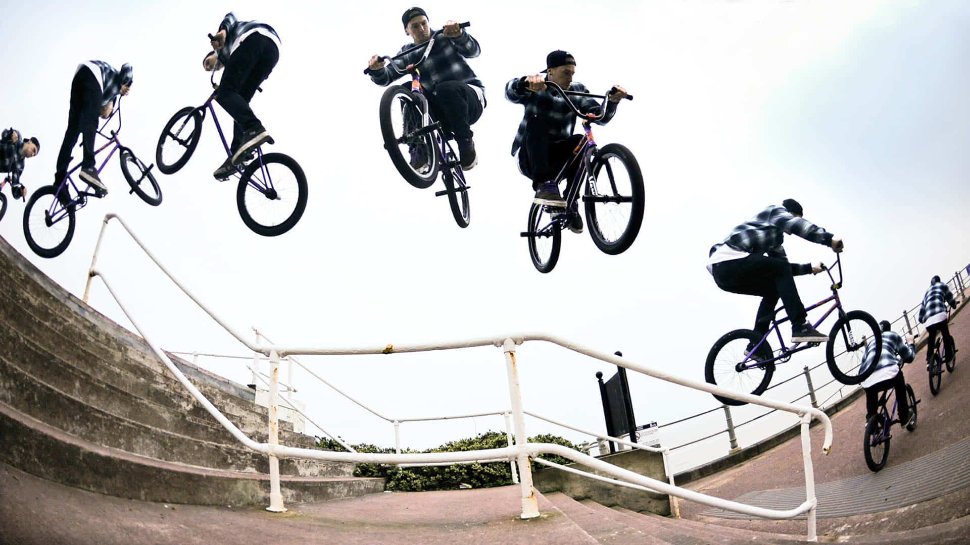 BMX車手在混凝土樓梯欄杆上空進行空中花式動作。