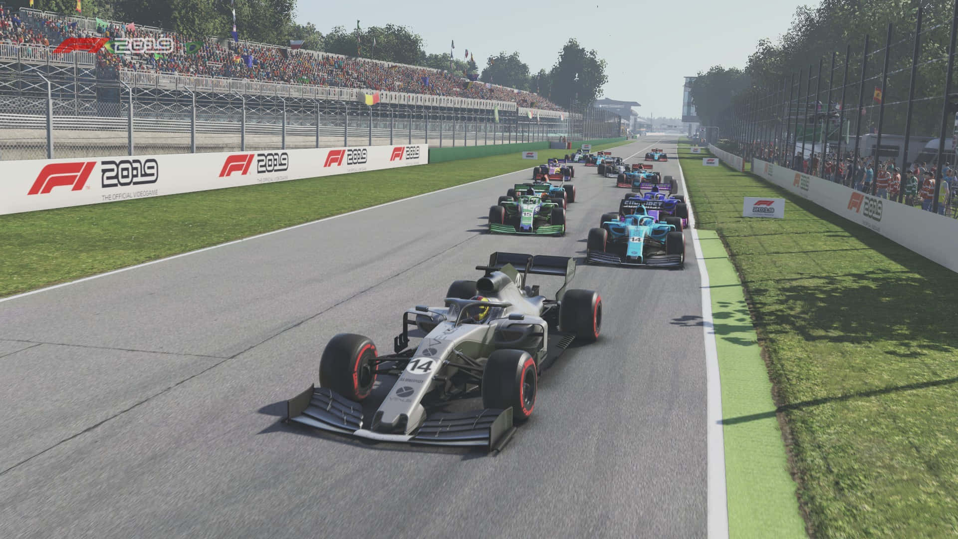 體驗 F1 2019 的刺激駕馭 壁紙 — 一架時尚的銀色一級方程式賽車，編號14，帶領著一群色彩繽紛的賽車在陽光普照的賽道上奔馳，看台上擠滿歡呼的人群。