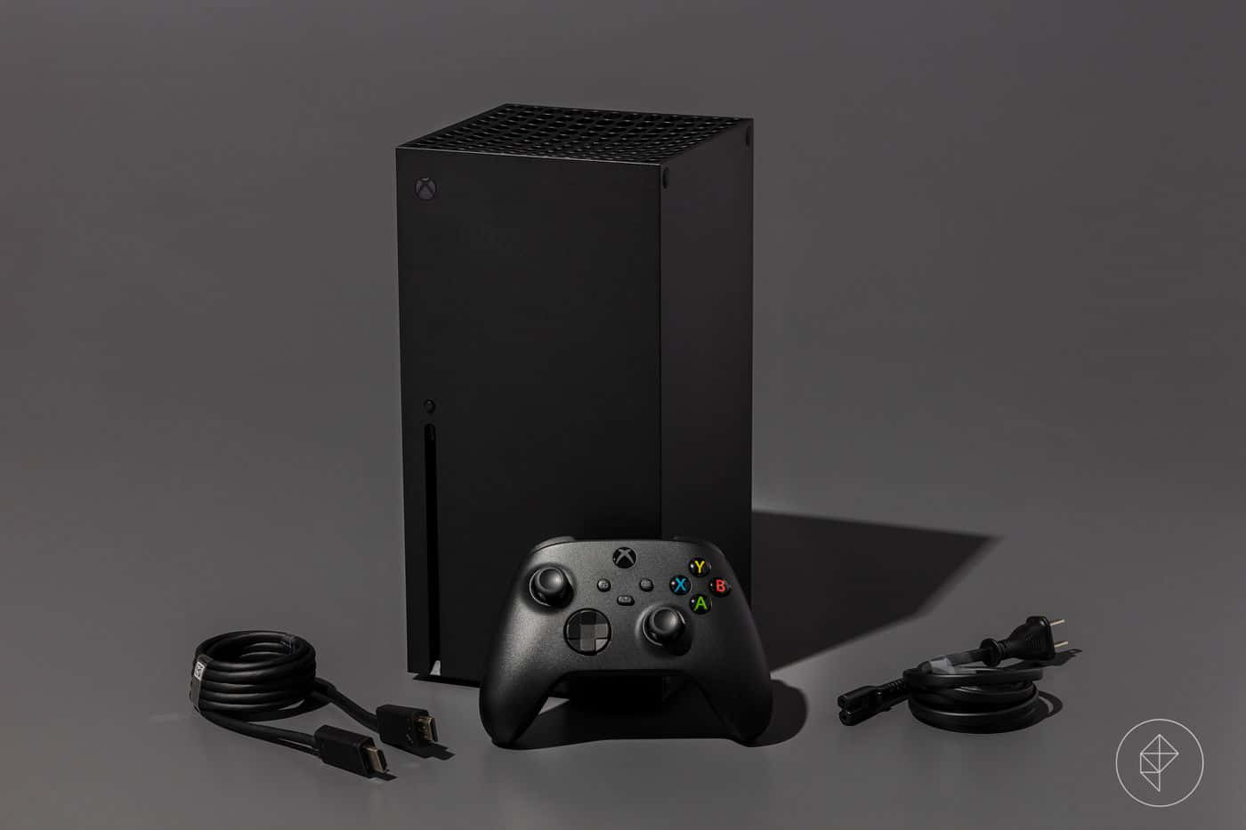 黑色 Xbox Series X 主機和手掣，附有電線，灰色背景。