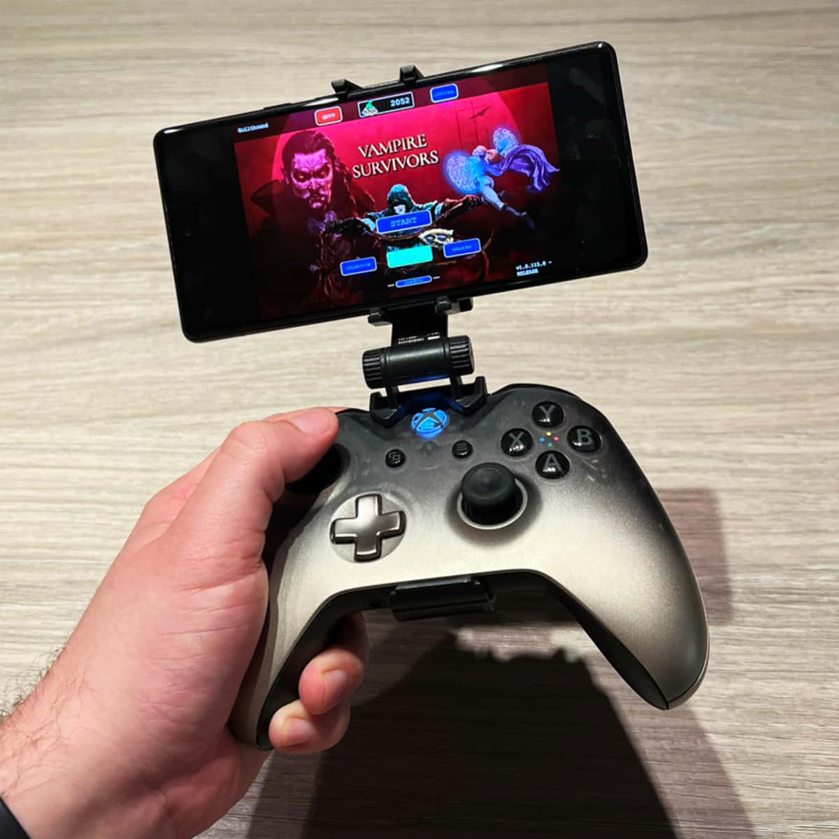 手拿著連接到手機的Xbox控制器玩Vampire Survivors遊戲。