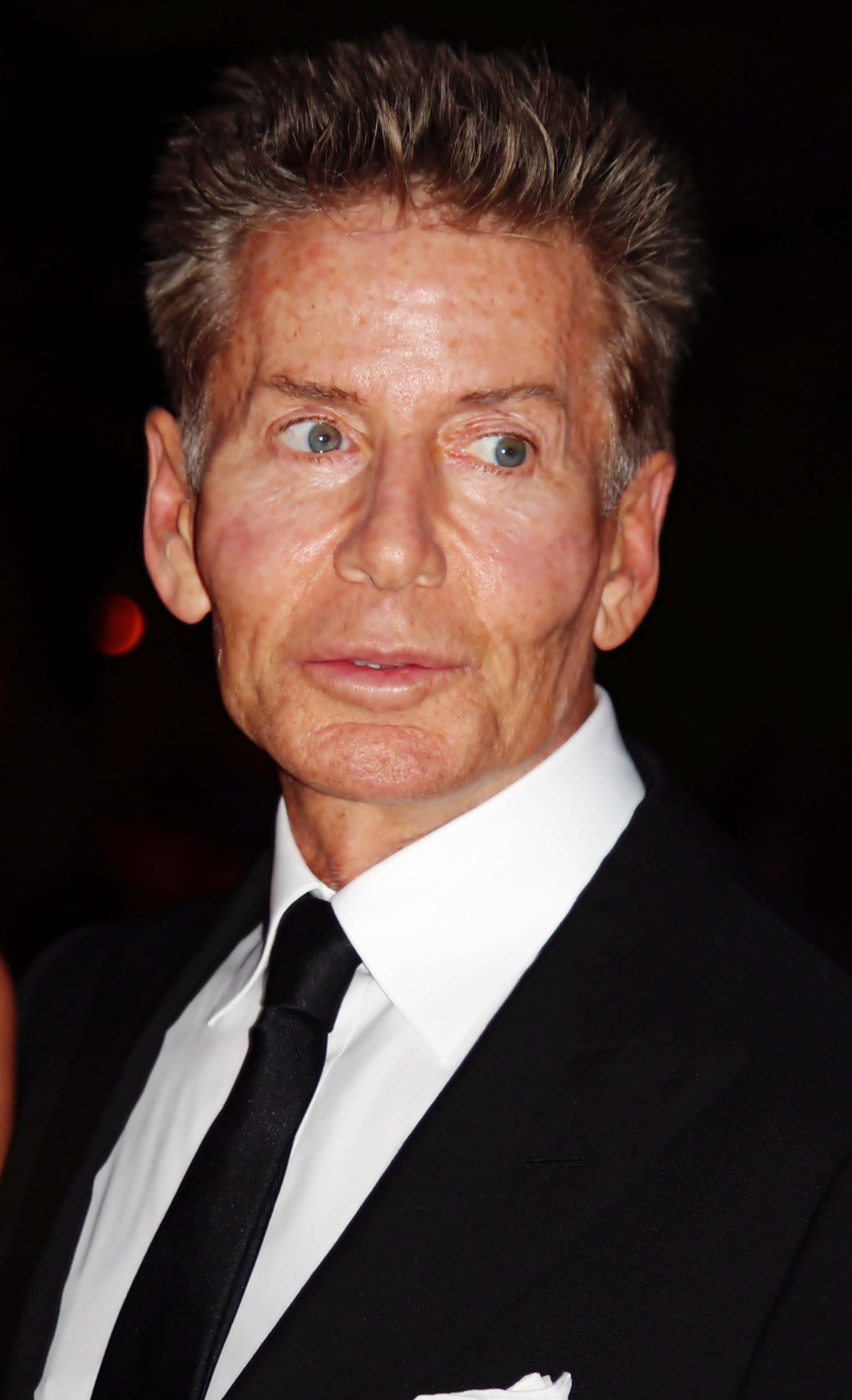 體驗Calvin Klein設計師的獨特魅力 壁紙 — 一名身穿黑色西裝和白色襯衫的男士特寫肖像，在深色背景下露出驚訝表情。