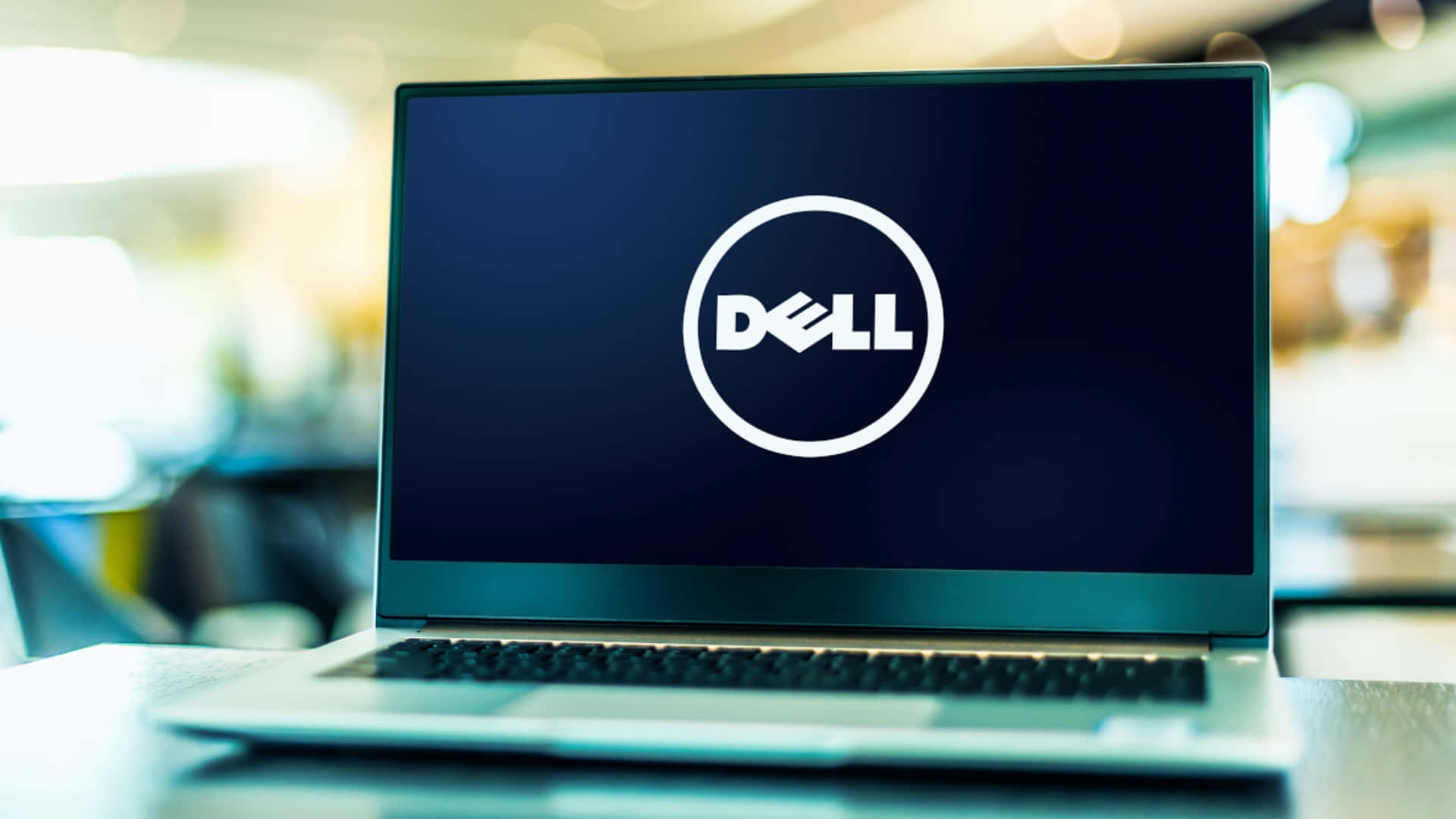 銀色手提電腦在辦公室環境中顯示Dell標誌