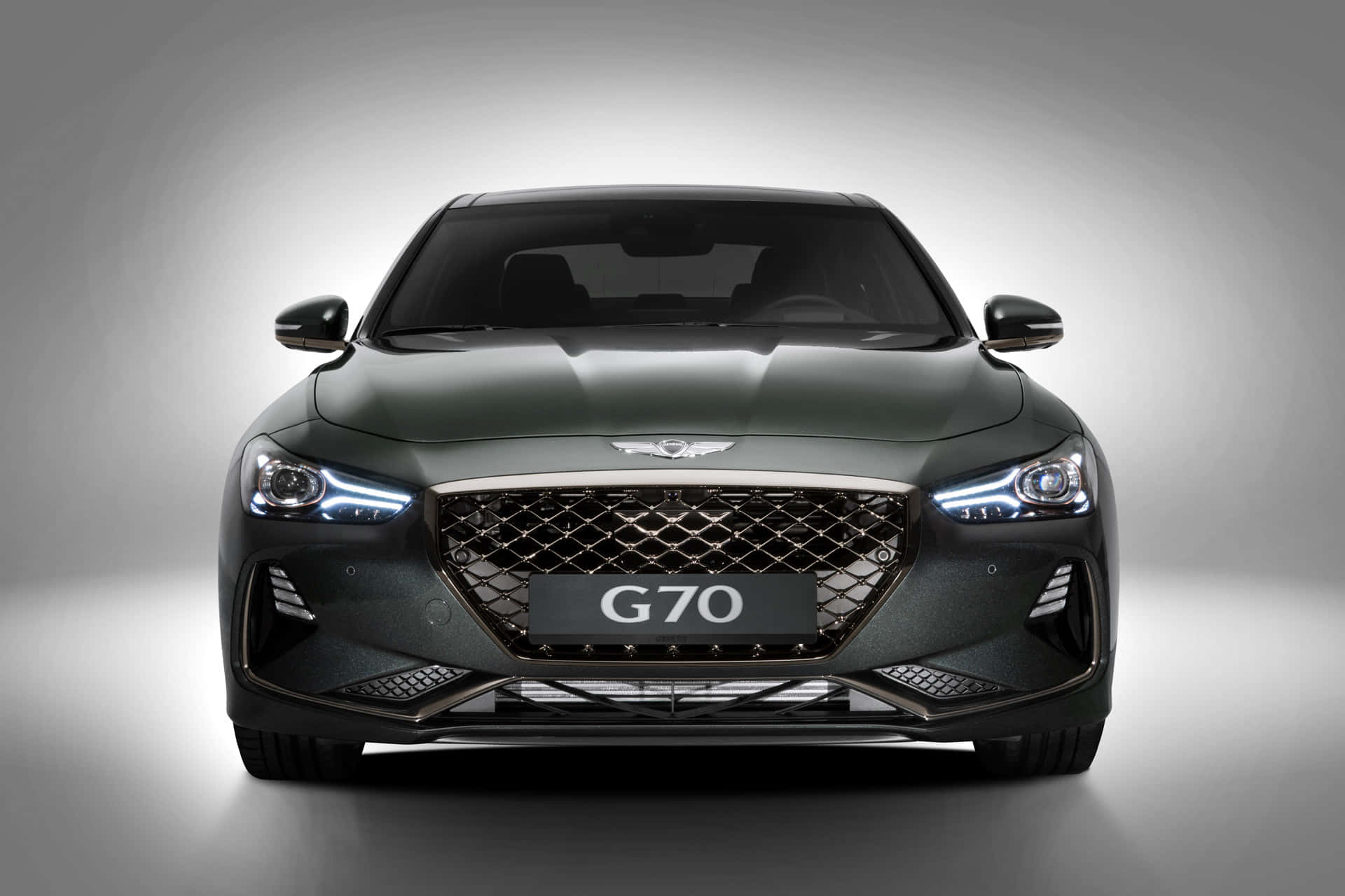 深綠色 Genesis G70 豪華轎車在工作室燈光下的正面視圖。