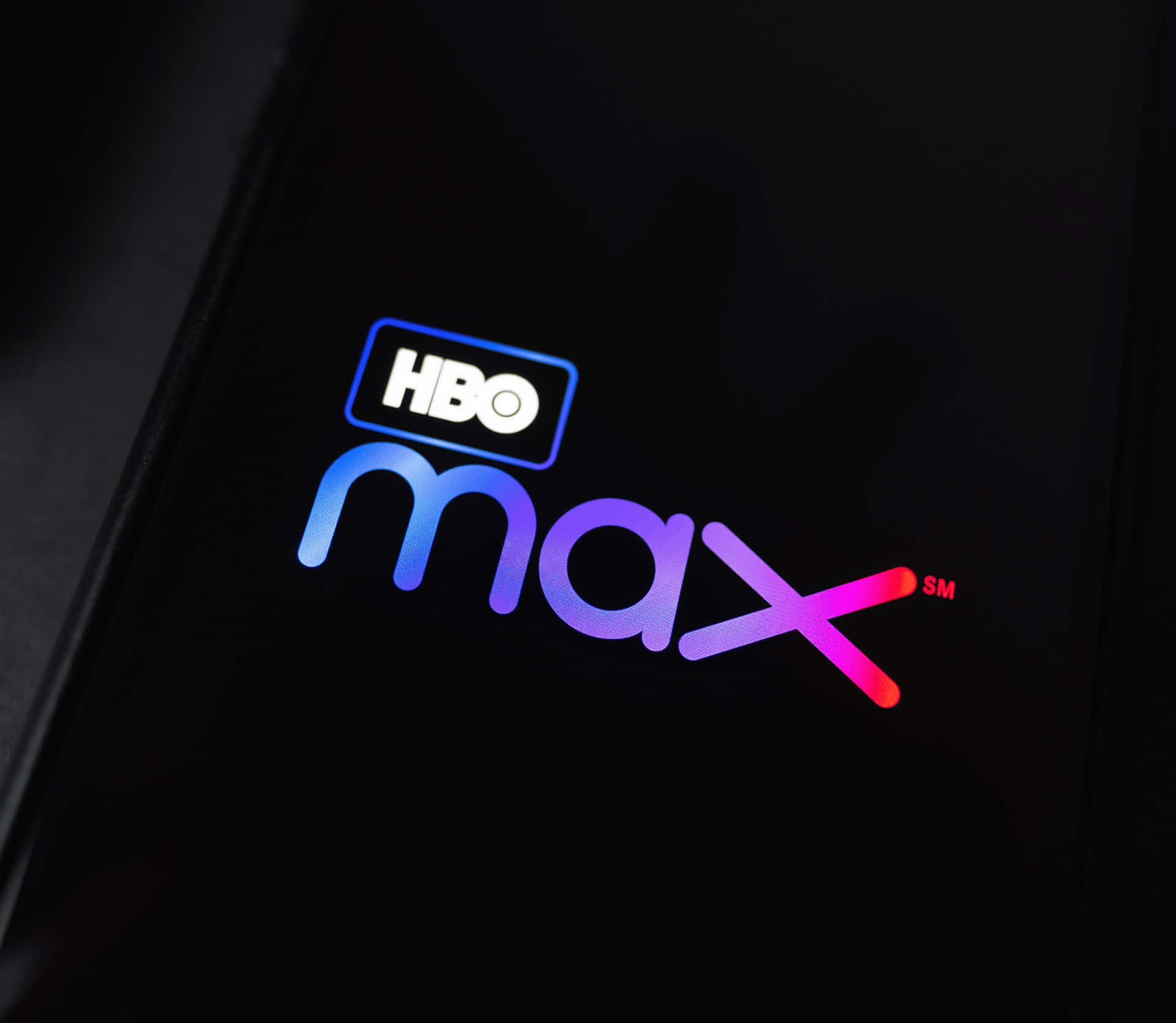 HBO Max 標誌顯示在智能手機屏幕上，帶有彩色漸變照明。
