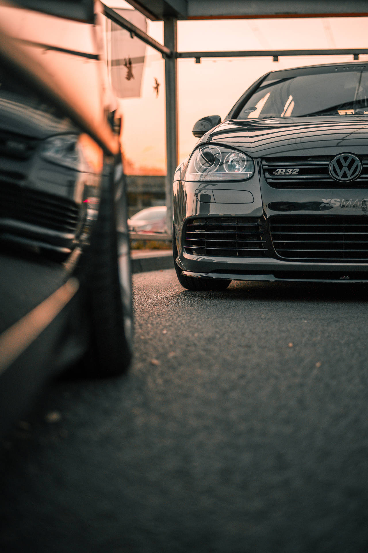黑色福士R32跑車在黃金時段停泊在車棚下，前景有動態模糊。