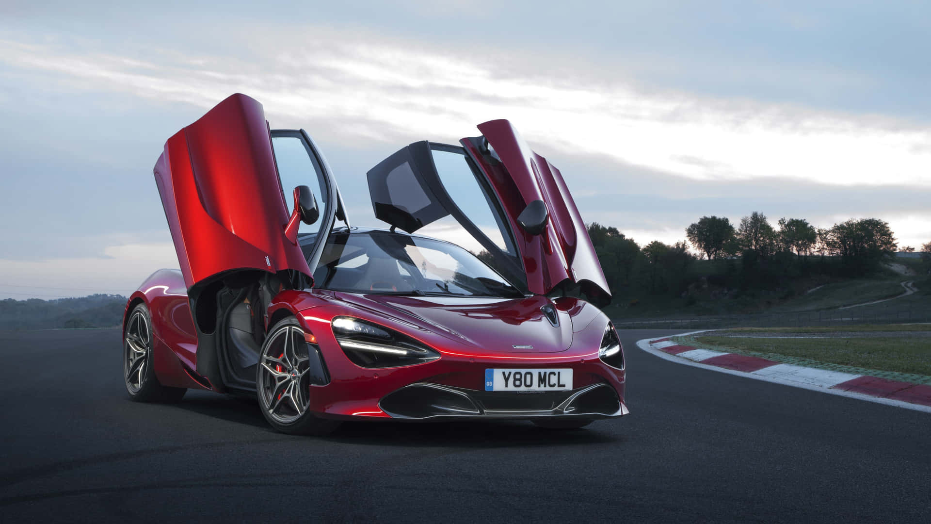 紅色McLaren跑車在賽道上打開鷗翼車門，時值黃昏。
