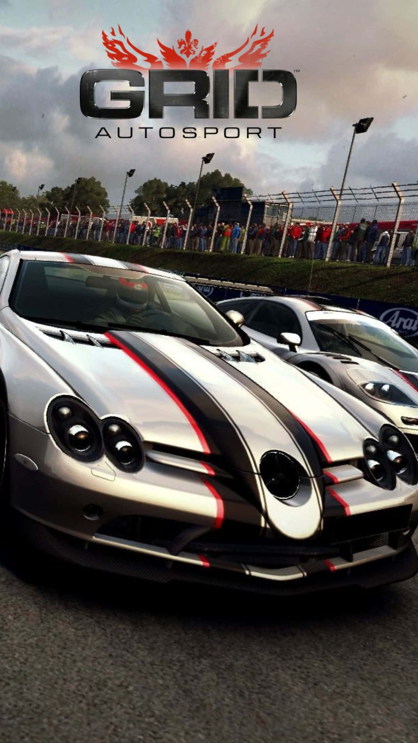 體驗刺激賽車快感 — Android Grid Autosport 壁紙 — 銀色賽車帶有黑色和紅色條紋，在陰天背景下排列在賽道上，背景有觀眾。