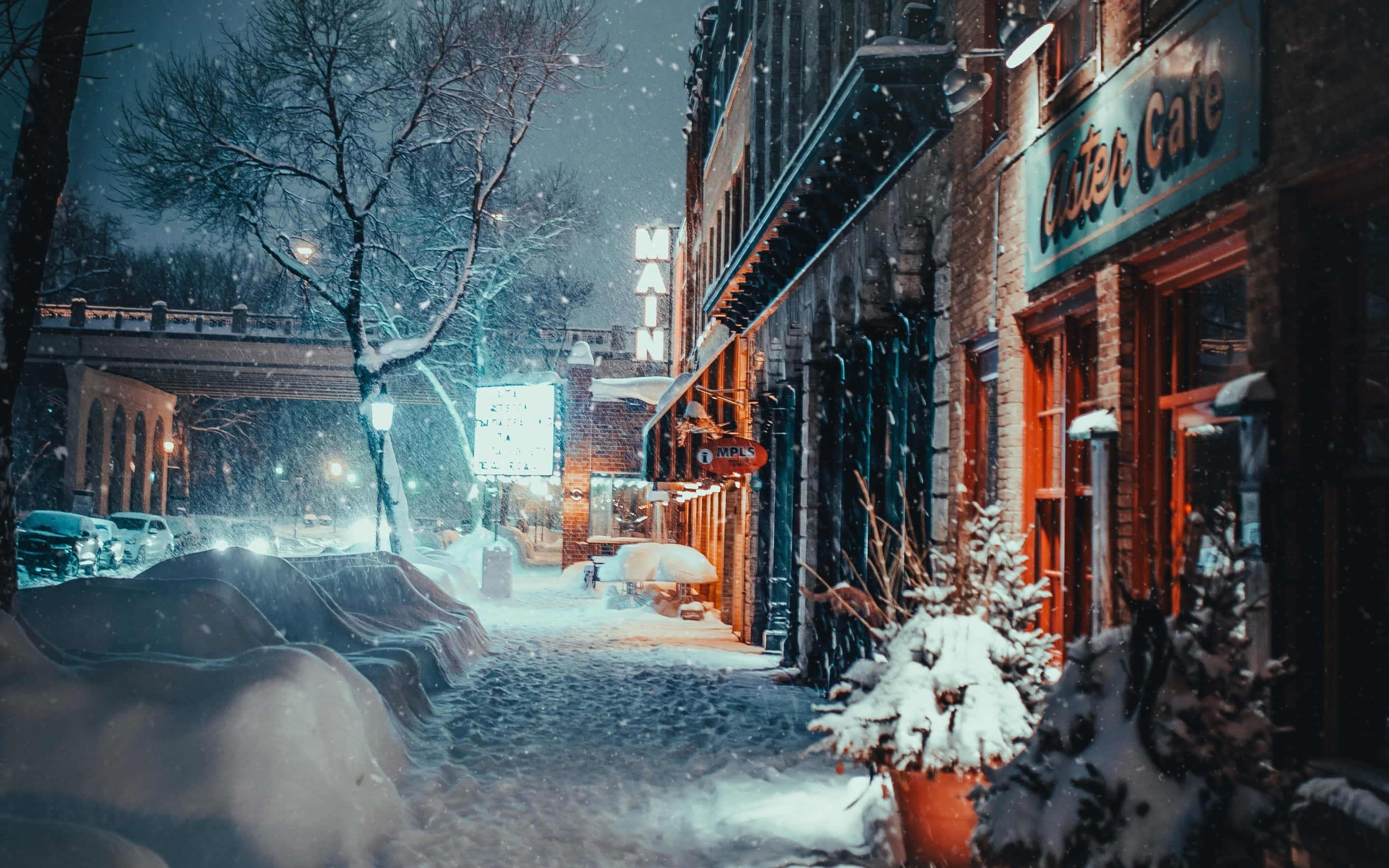 體驗前所未有的暴雪奇景 壁紙 — 白雪覆蓋寧靜的城市街道，夜晚時分，店舖櫥窗的溫暖燈光映照著飄落的雪花。