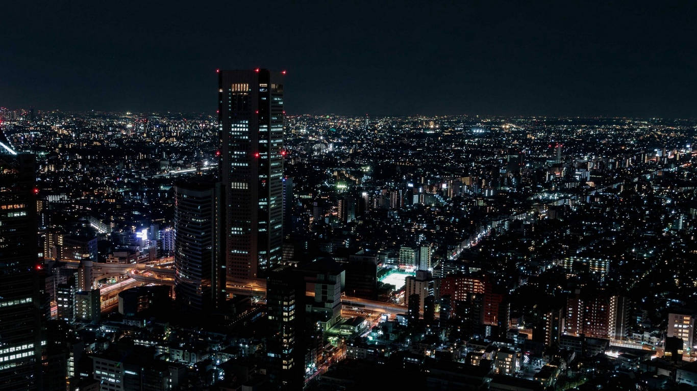 密集市區的夜間高空照片，建築物和街道閃閃發光。