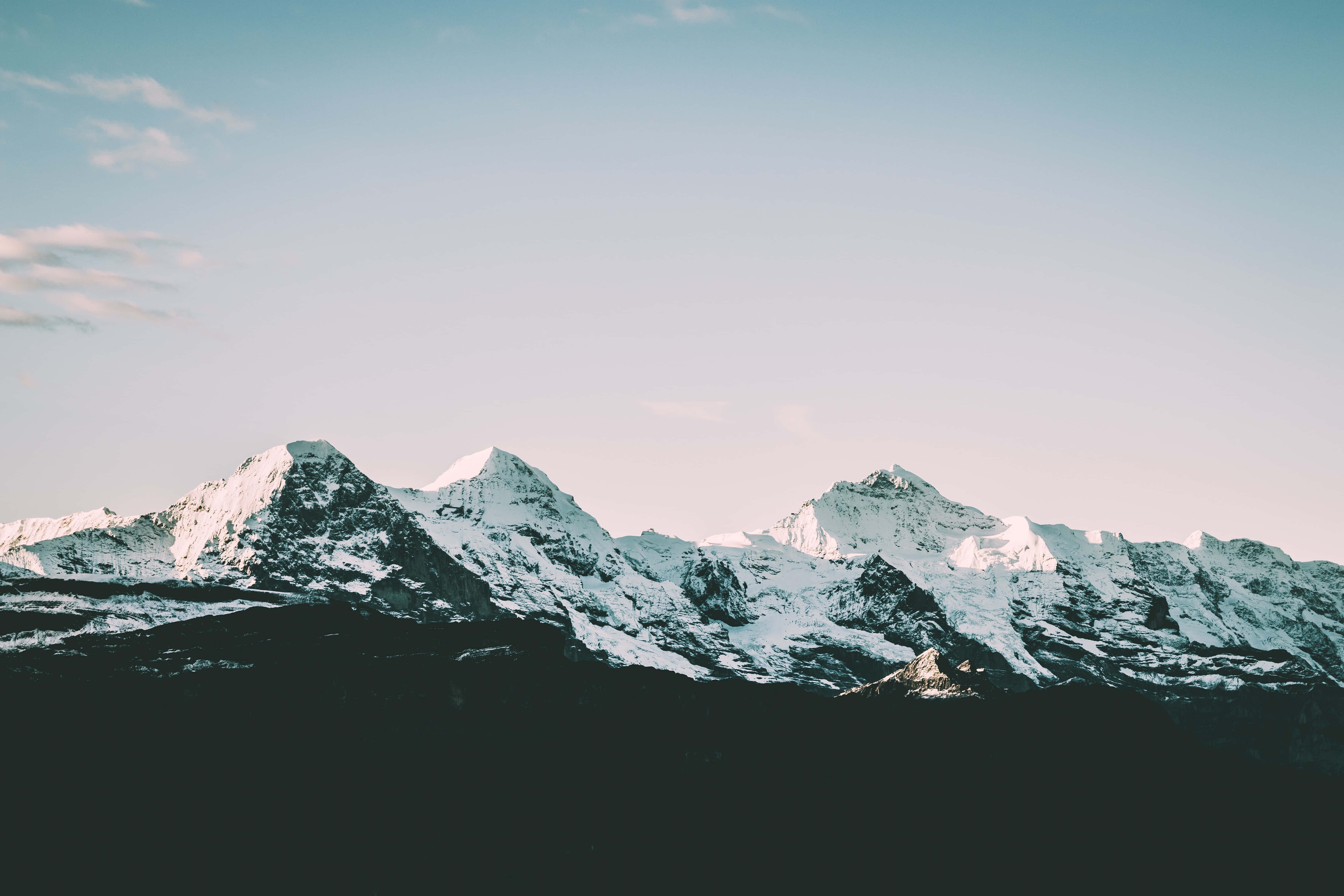 體驗大自然之美，免費背景 壁紙 — 白雪覆蓋的山峰在帶有縷縷雲彩的柔和漸變天空襯托下巍然聳立。